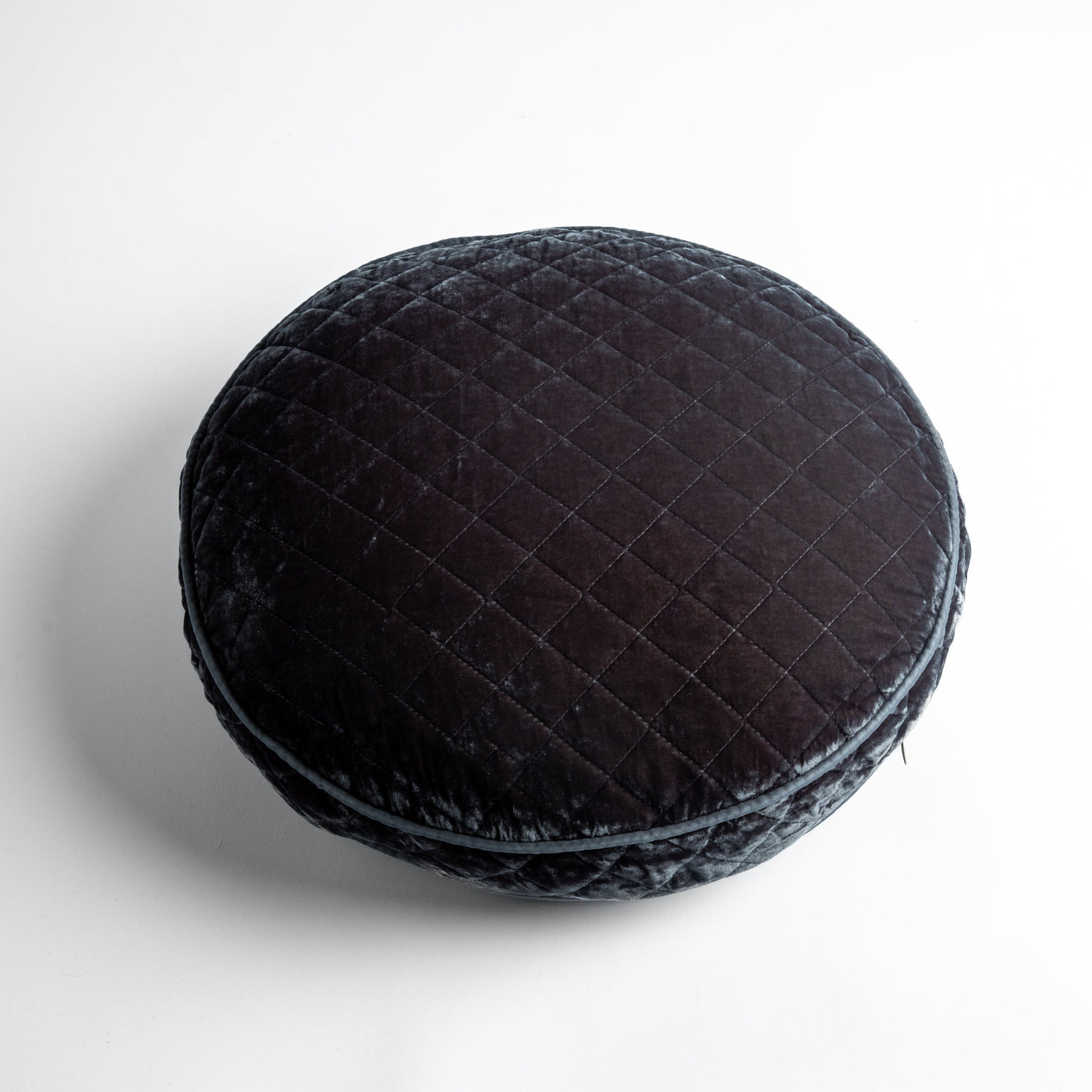 Close-up of Bella Notte round quilted silk velvet throw pillow in deep charcoal, grid-stitched texture.