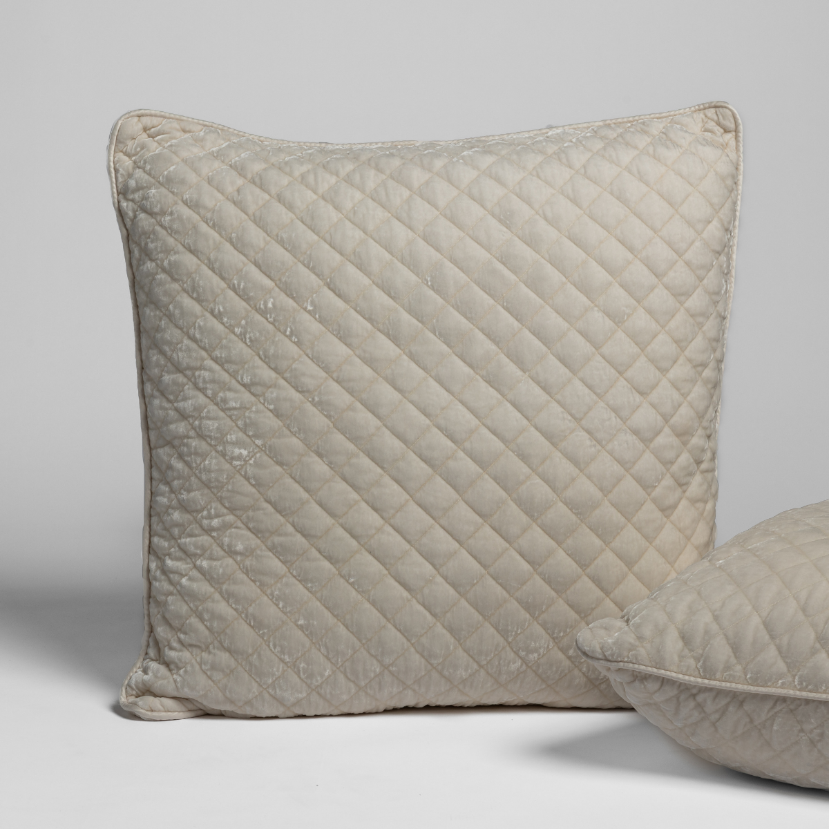 Bella Notte Silk Velvet Quilted Sham in Crema, angled view showing diamond quilt pattern and piped edge.