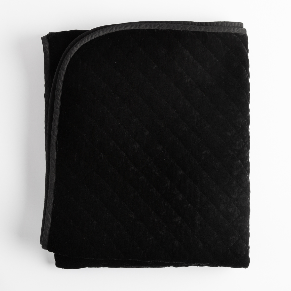 Folded Corvino silk velvet quilted blanket with charcoal contrast trim, diagonal quilting detail.