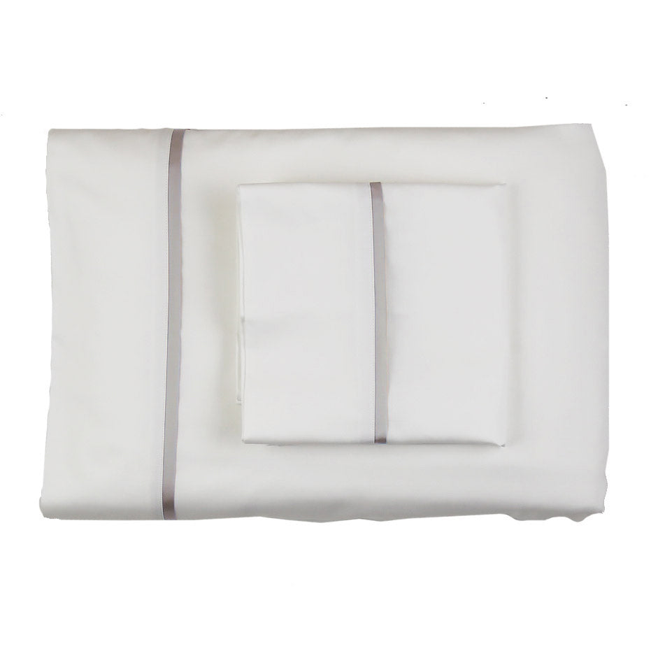 Folded white sheet set with silver silk trim detail, overhead flat lay view.