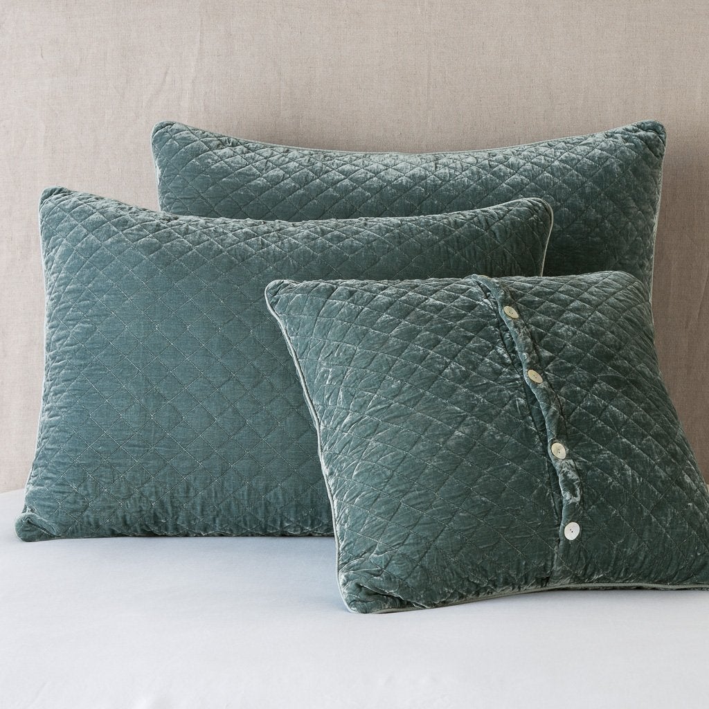 Three Bella Notte Silk Velvet quilted shams in Eucalyptus, diamond stitching, button detail on smallest.
