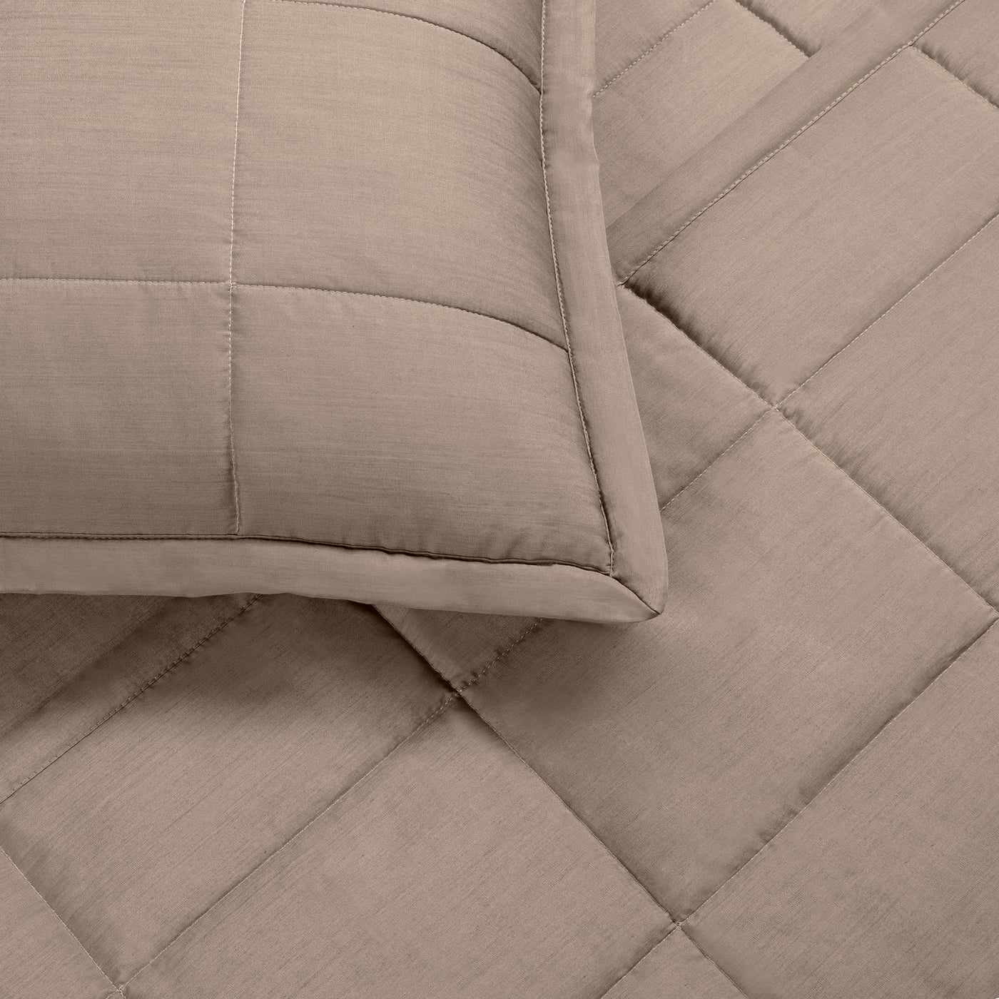 Close-up of Ann Gish Slub coverlet in taupe, showing diamond quilting and pillow sham corner.
