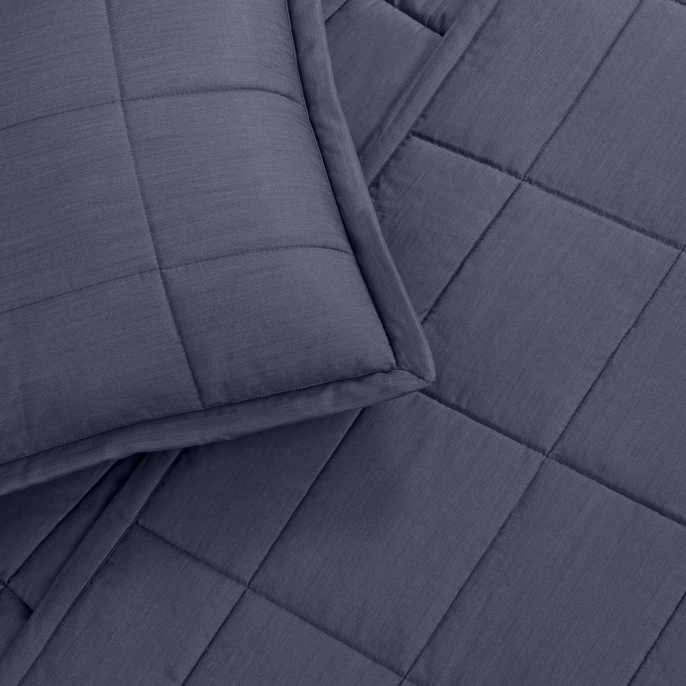 Close-up of Ann Gish Slub Tencel coverlet corner in slate blue with grid quilting detail.