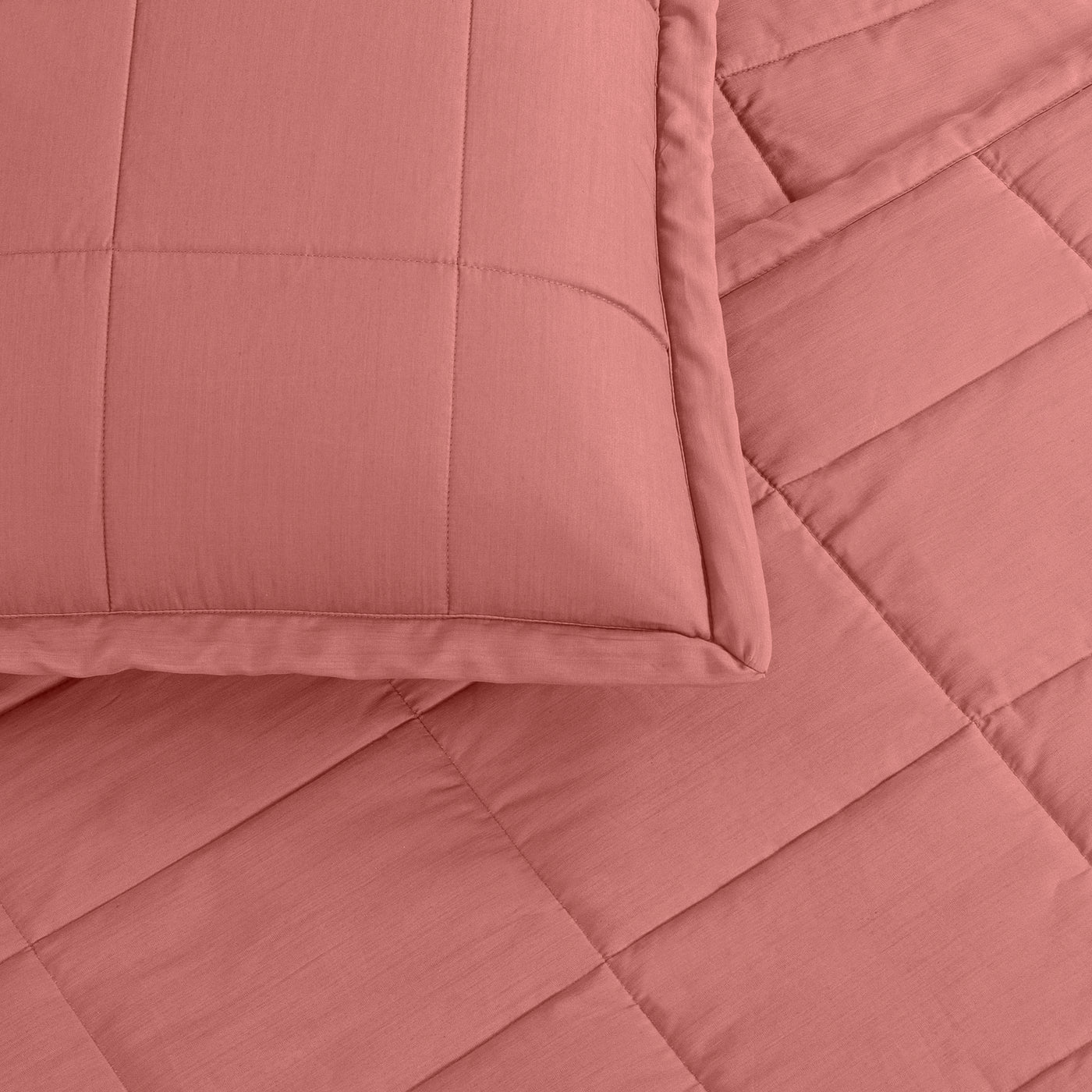 Close-up of Ann Gish Slub coverlet corner with matching sham in dusty rose, diamond quilting detail.