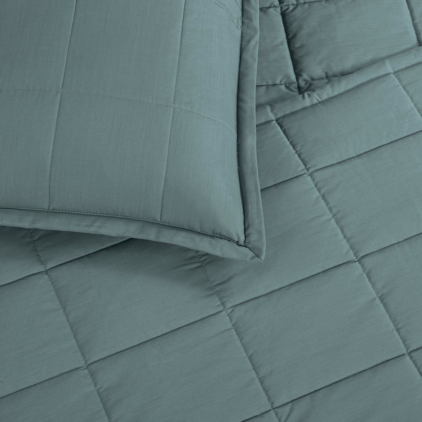 Close-up of Ann Gish Slub Tencel coverlet set in teal, showing grid quilting and matching sham.
