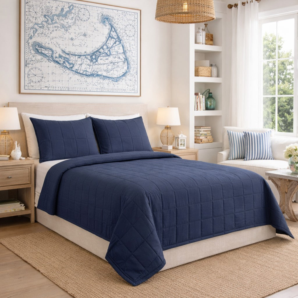 Navy blue Ann Gish Slub Tencel coverlet set styled on bed in coastal-themed bedroom.
