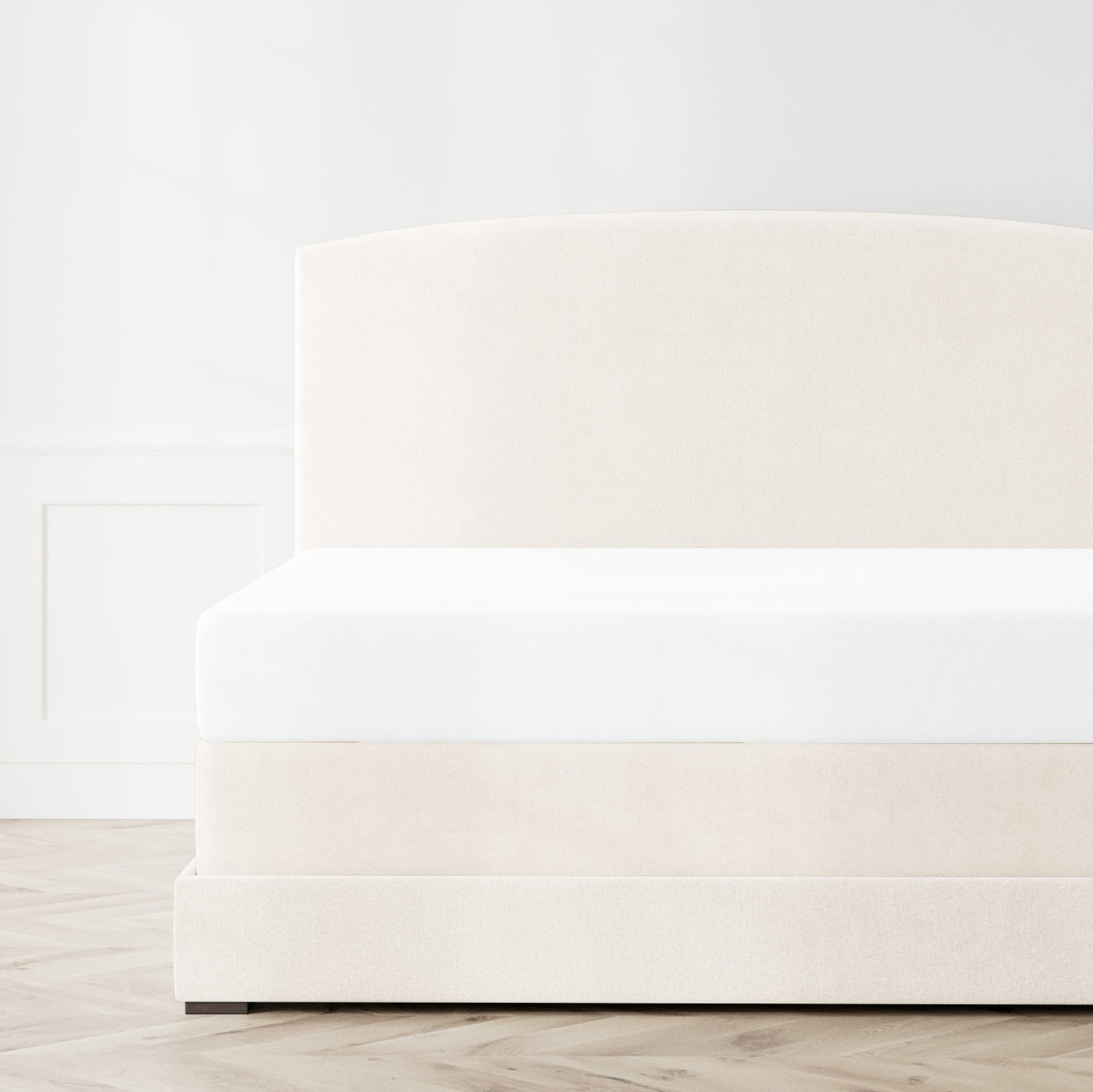 Crisp white box spring cover on an ivory upholstered bed, side-angle view showing clean tailored fit.
