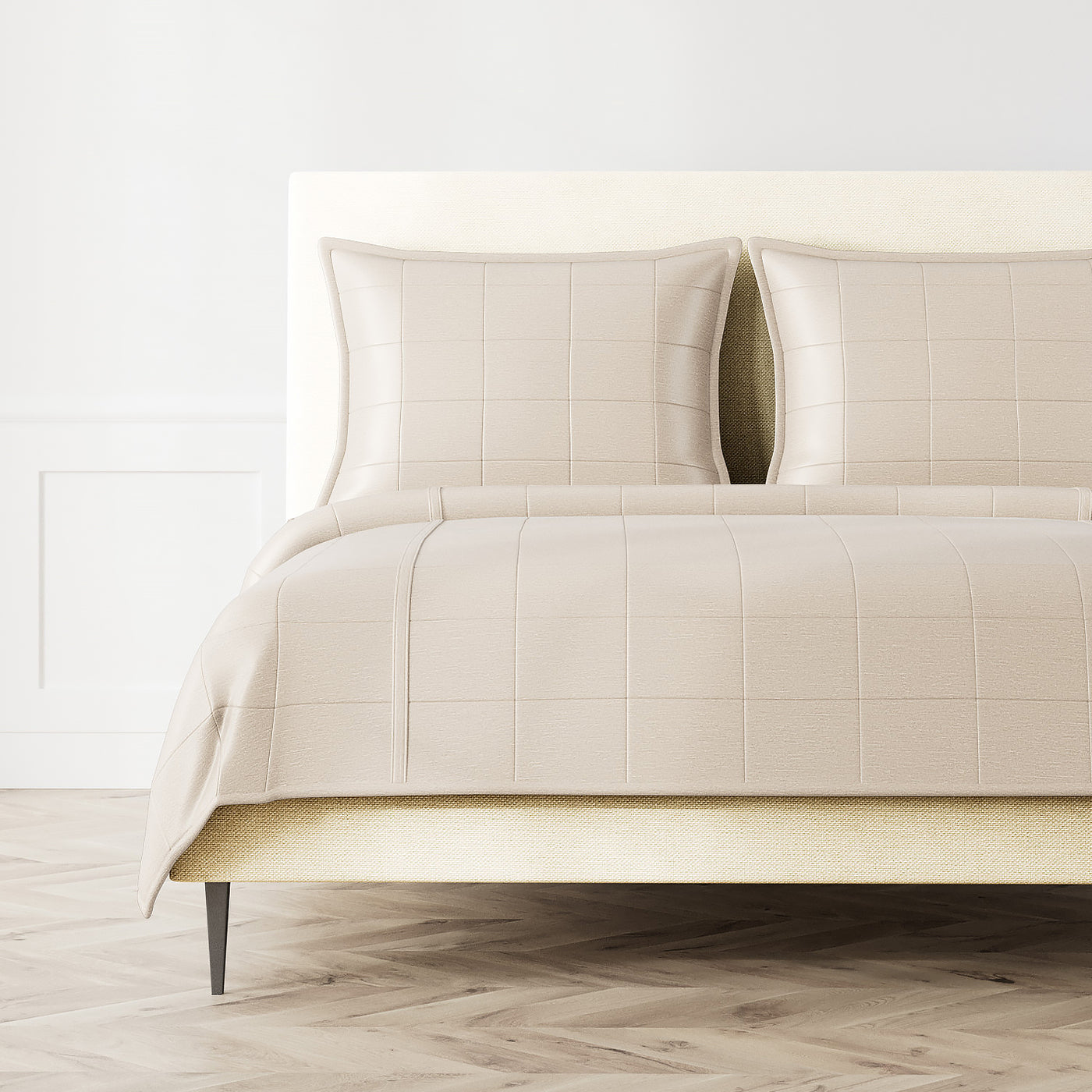 Ann Gish Stria coverlet in ivory, styled on bed with matching shams, grid-stitch quilting detail.