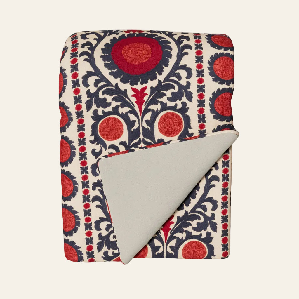 Ann Gish Suzani throw, ivory with red and navy medallion print, grey reverse folded corner.