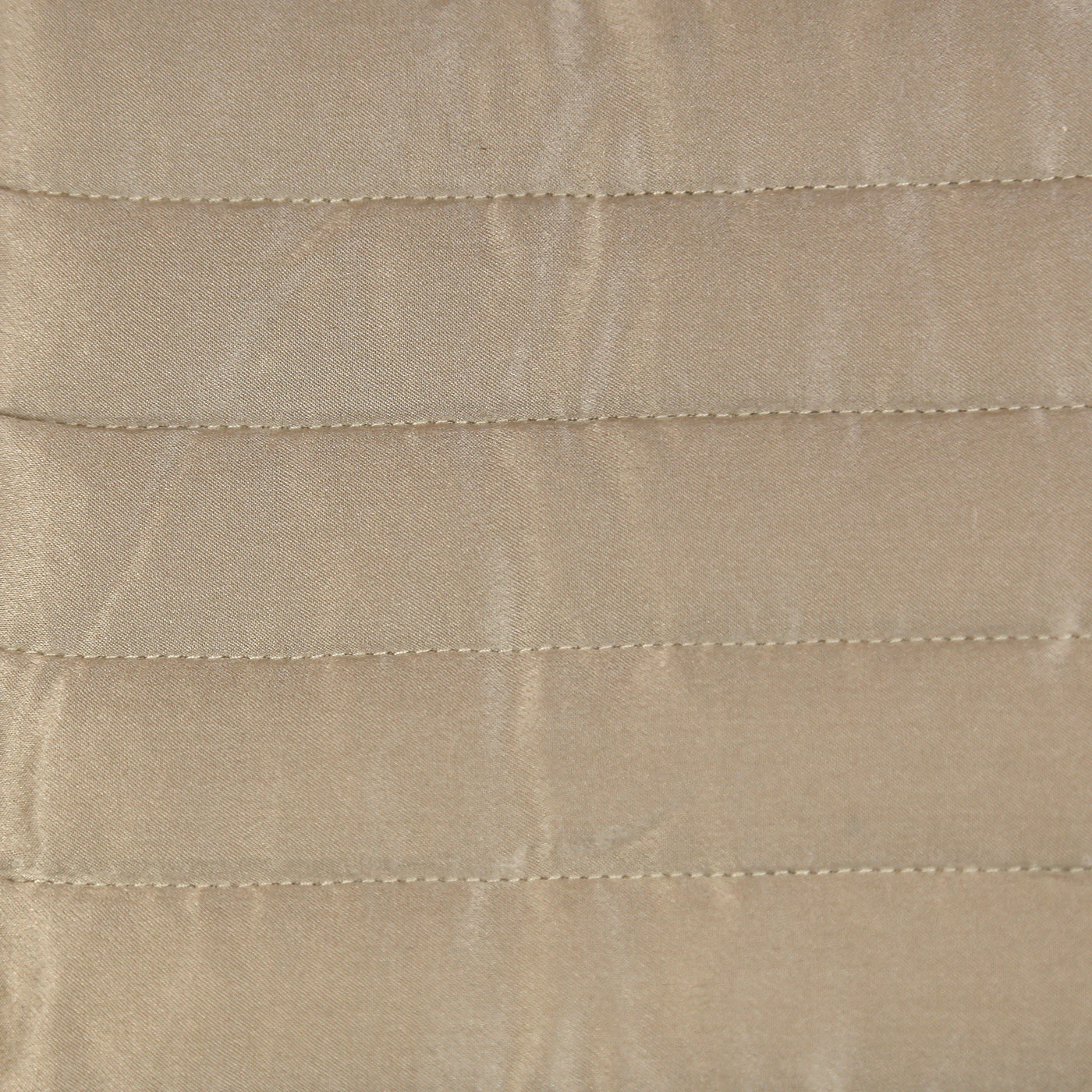 Close-up of champagne charmeuse fabric with horizontal channel-stitched quilting detail.