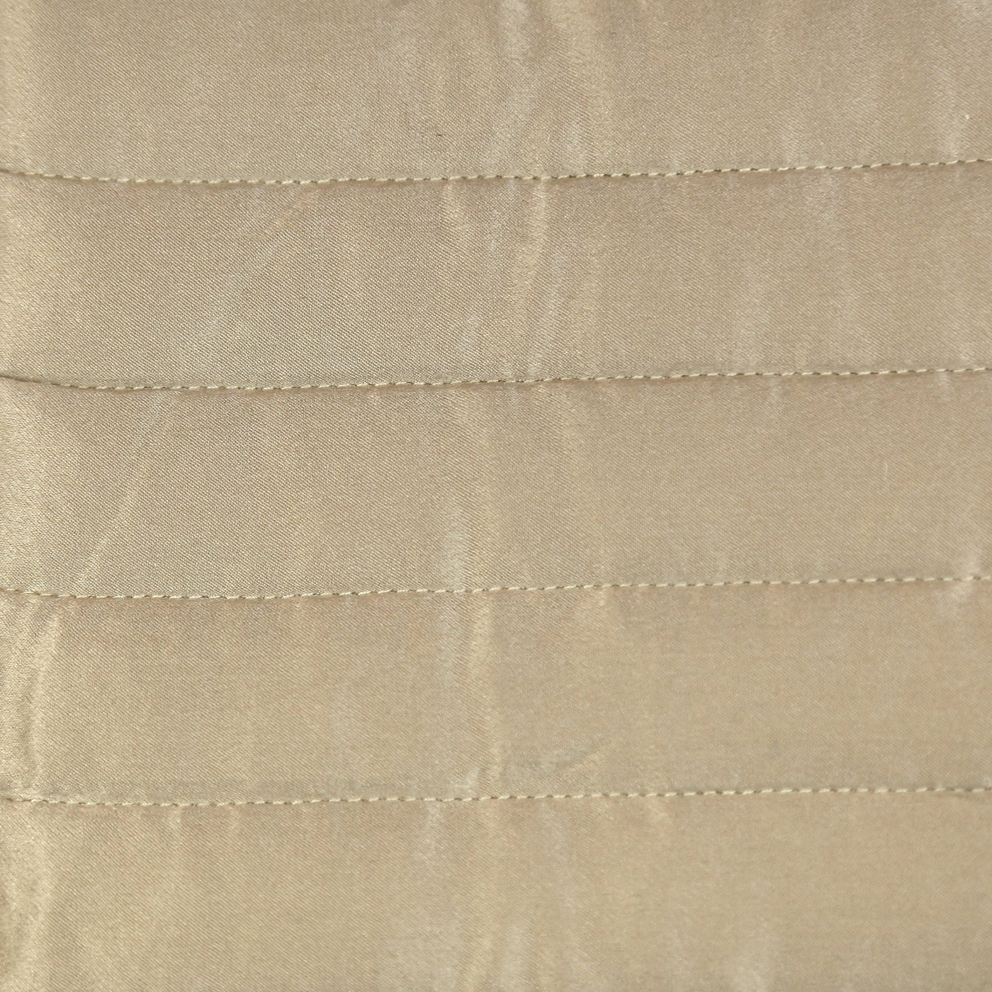 Close-up of champagne charmeuse fabric with horizontal channel quilting stitching detail.
