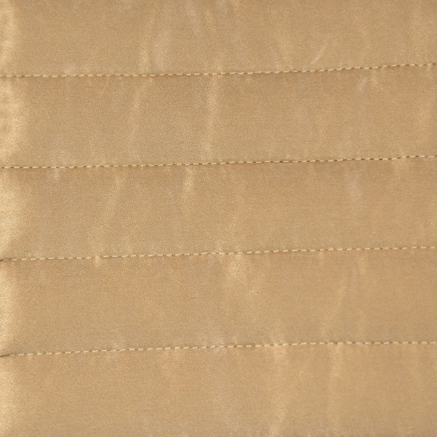 Close-up of champagne charmeuse fabric with horizontal channel quilting stitching detail.