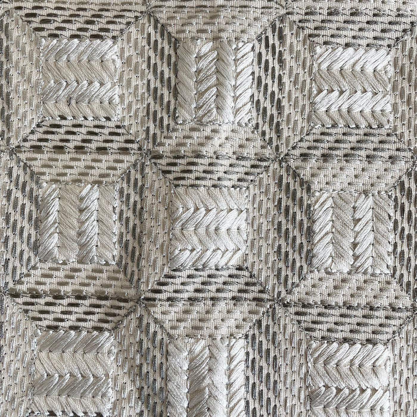 Close-up of Ann Gish Collonade pillow fabric with geometric woven pattern in silver and ivory.