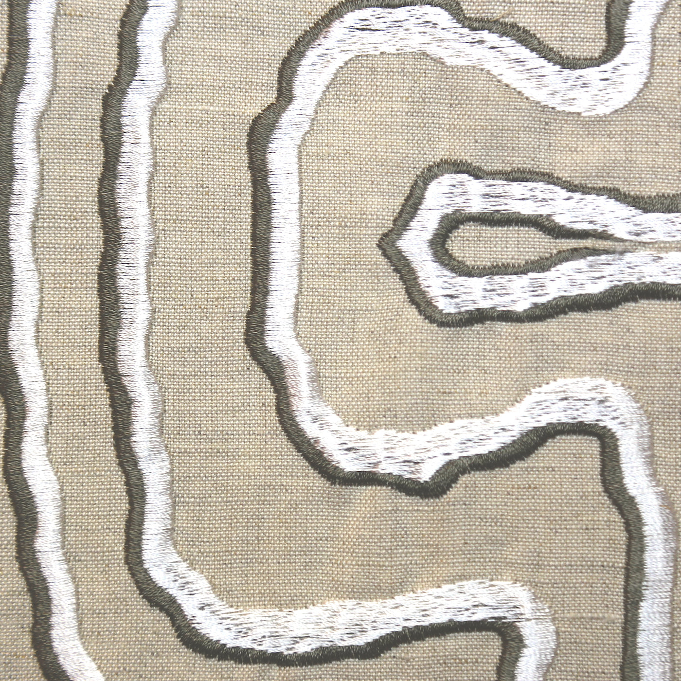 Close-up of white and charcoal embroidered contour lines on natural linen pillow fabric.
