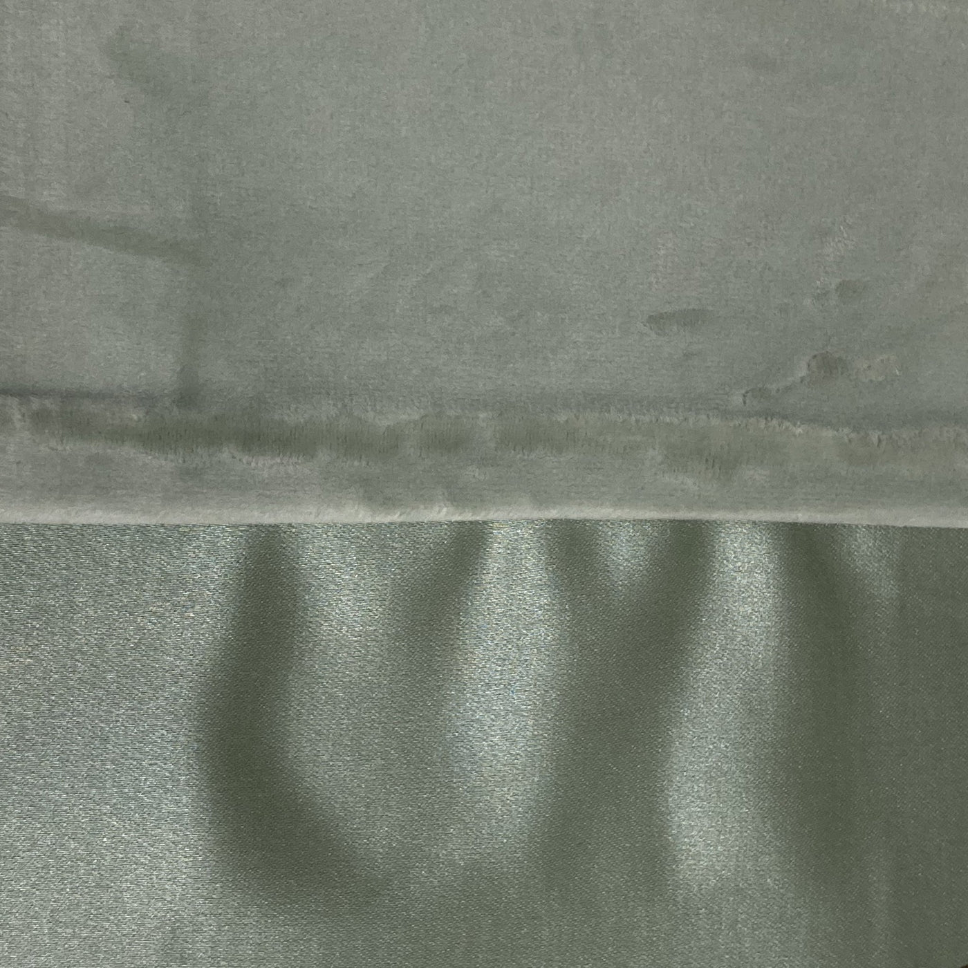Close-up of sage velvet and satin reverse fabrics meeting at a stitched seam.