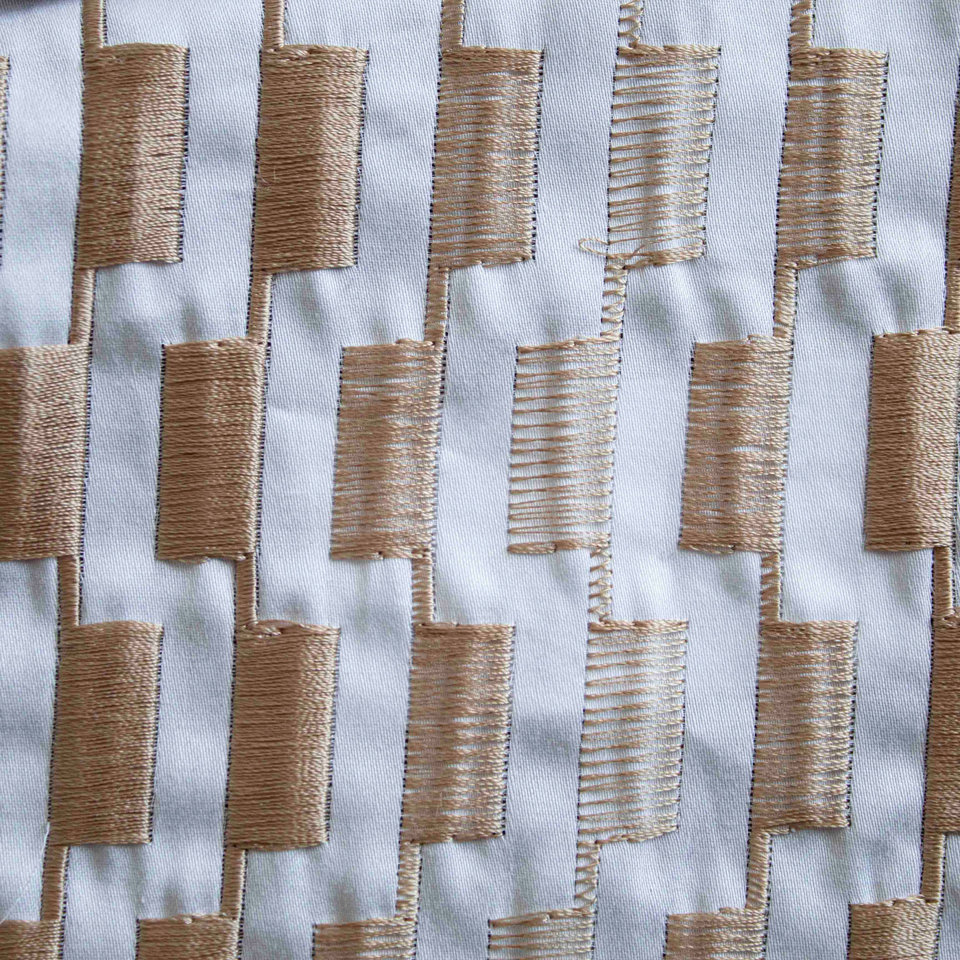 Close-up of Ann Gish Ingot duvet cover showing champagne embroidered rectangular blocks on white fabric.
