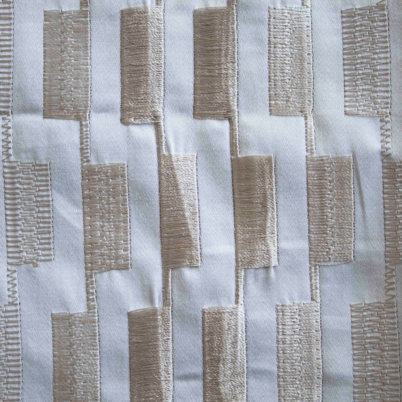 Close-up of Ann Gish Ingot duvet cover showing champagne embroidered rectangular blocks on ivory fabric.
