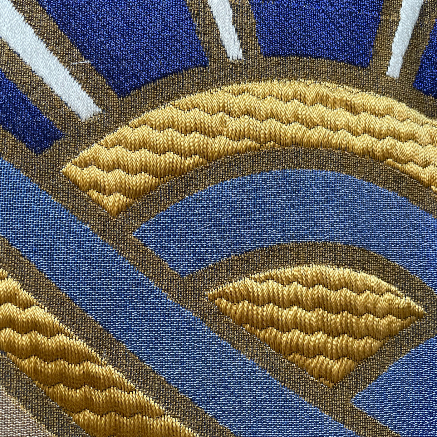 Close-up of Ann Gish Lever Du Soleil pillow jacquard weave in cobalt, gold, and bronze.