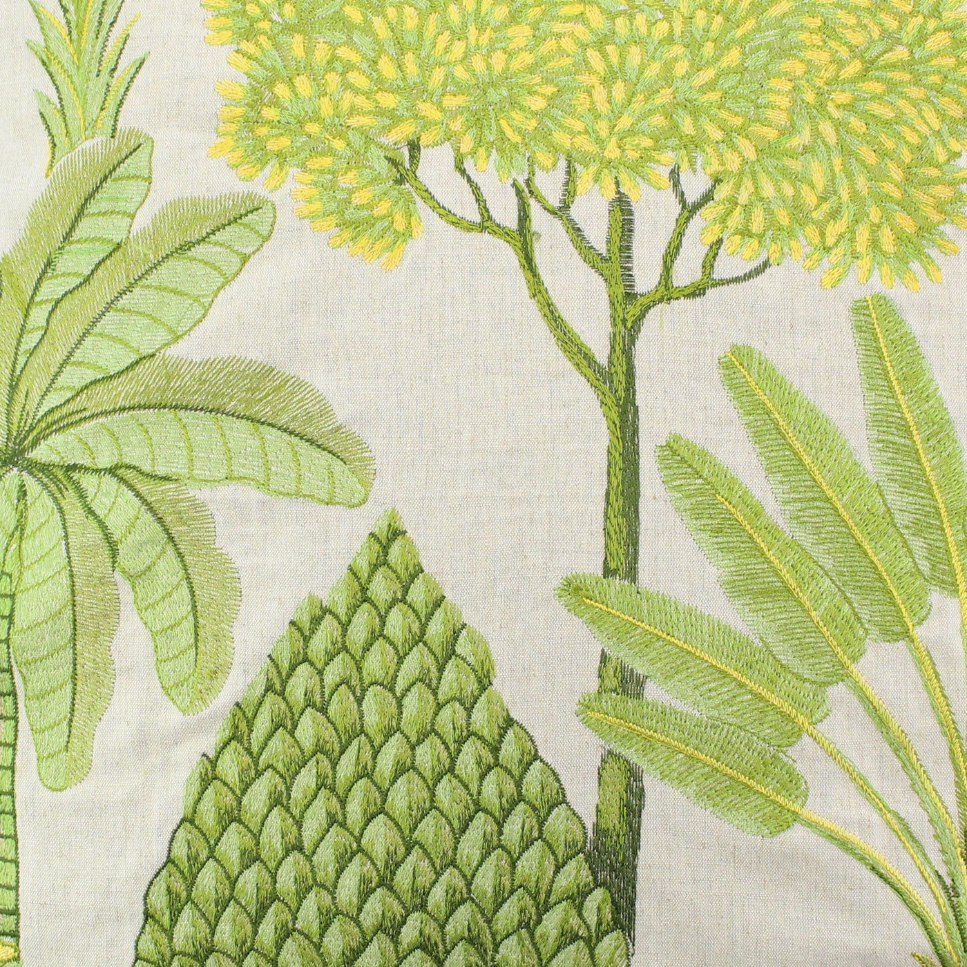 Close-up of green and yellow tropical botanical embroidery on ivory linen pillow fabric.
