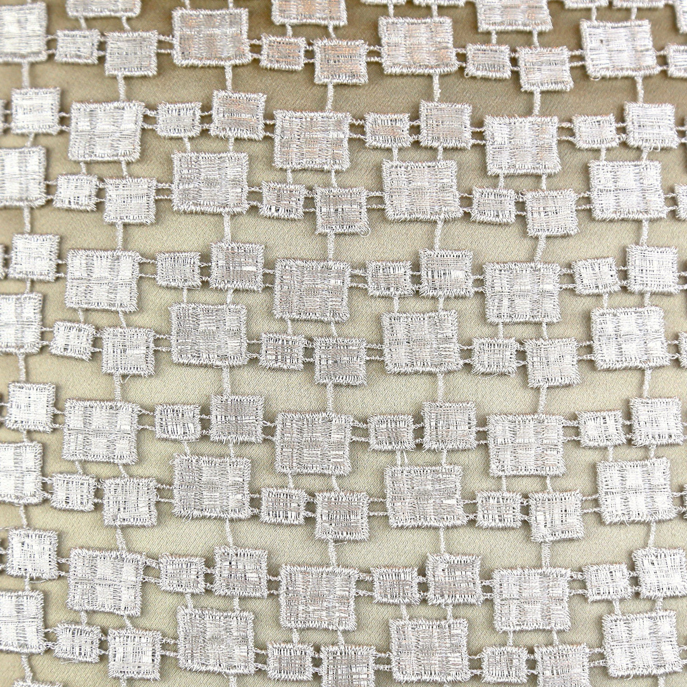 Close-up of ivory and silver metallic woven square mosaic pattern on Ann Gish pillow fabric.