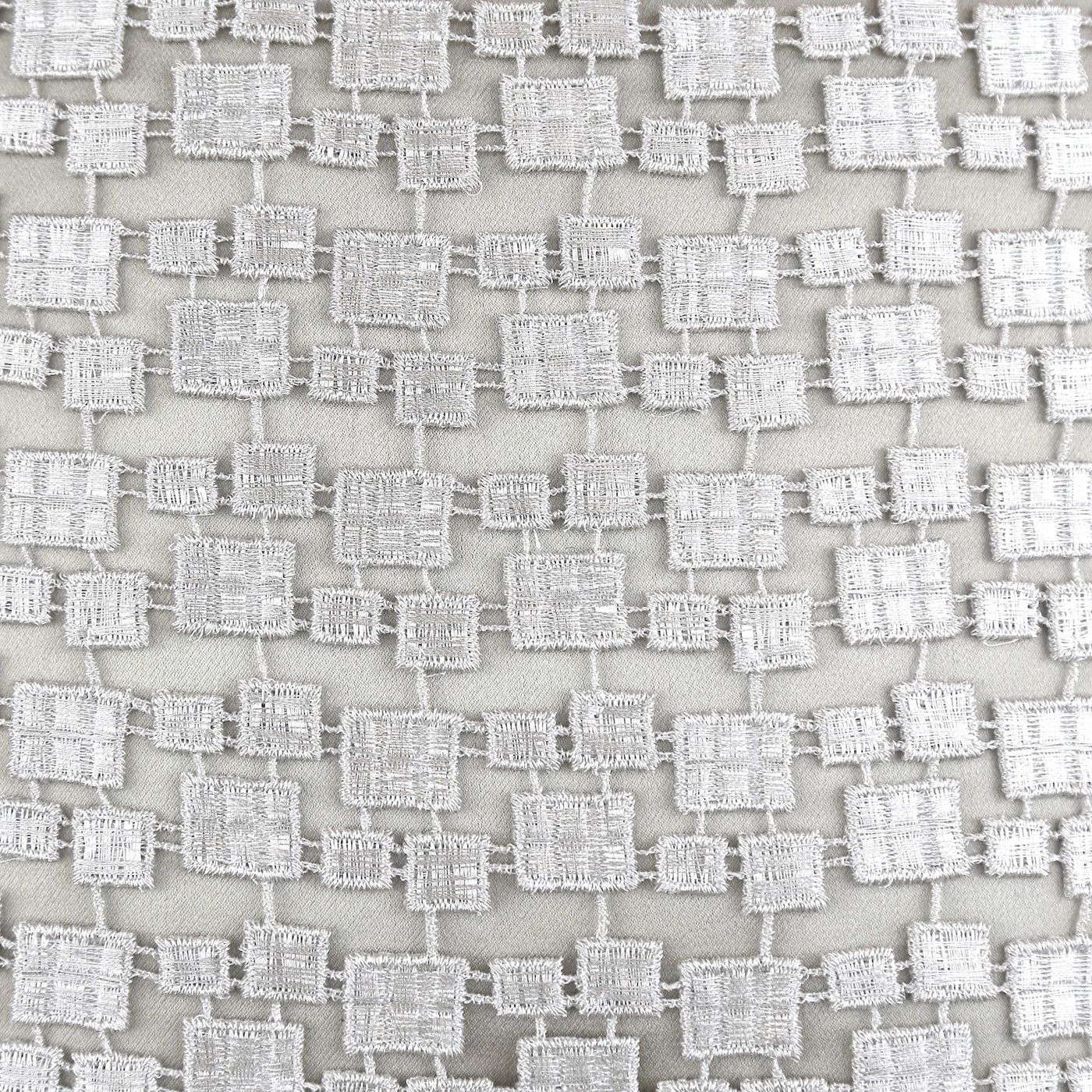 Close-up of Ann Gish Metallic Mosaic Pillow fabric, ivory woven square grid texture.