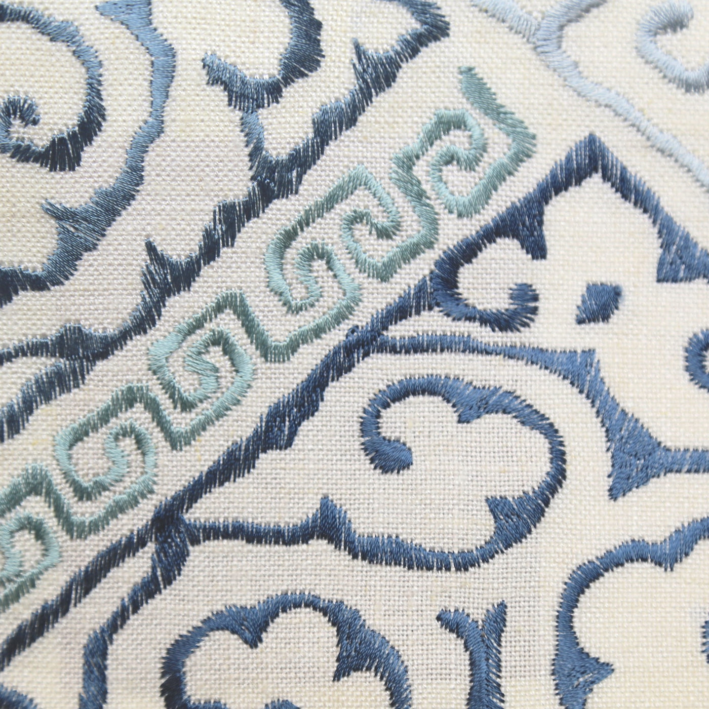 Close-up of Ann Gish Oporto duvet cover showing blue and aqua embroidery on ivory linen.