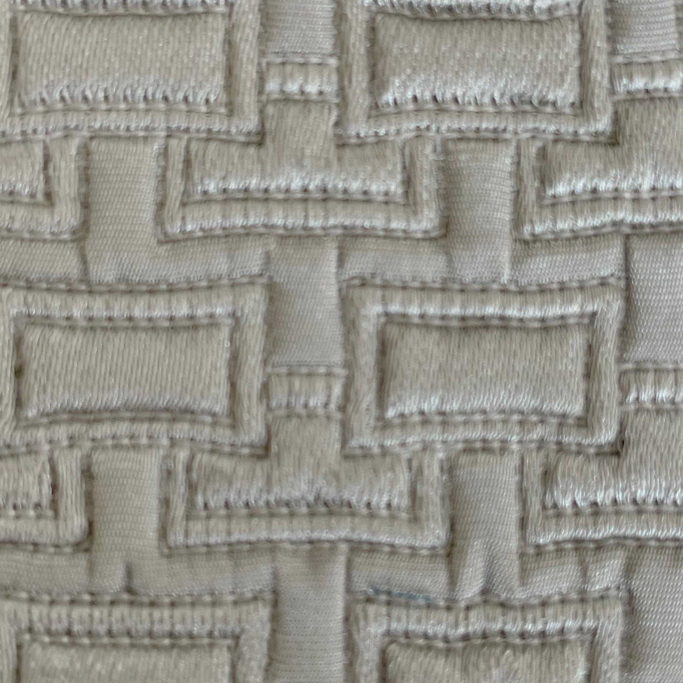 Close-up of Ann Gish Pavilion pillow fabric with geometric rectangular embroidery in ivory.