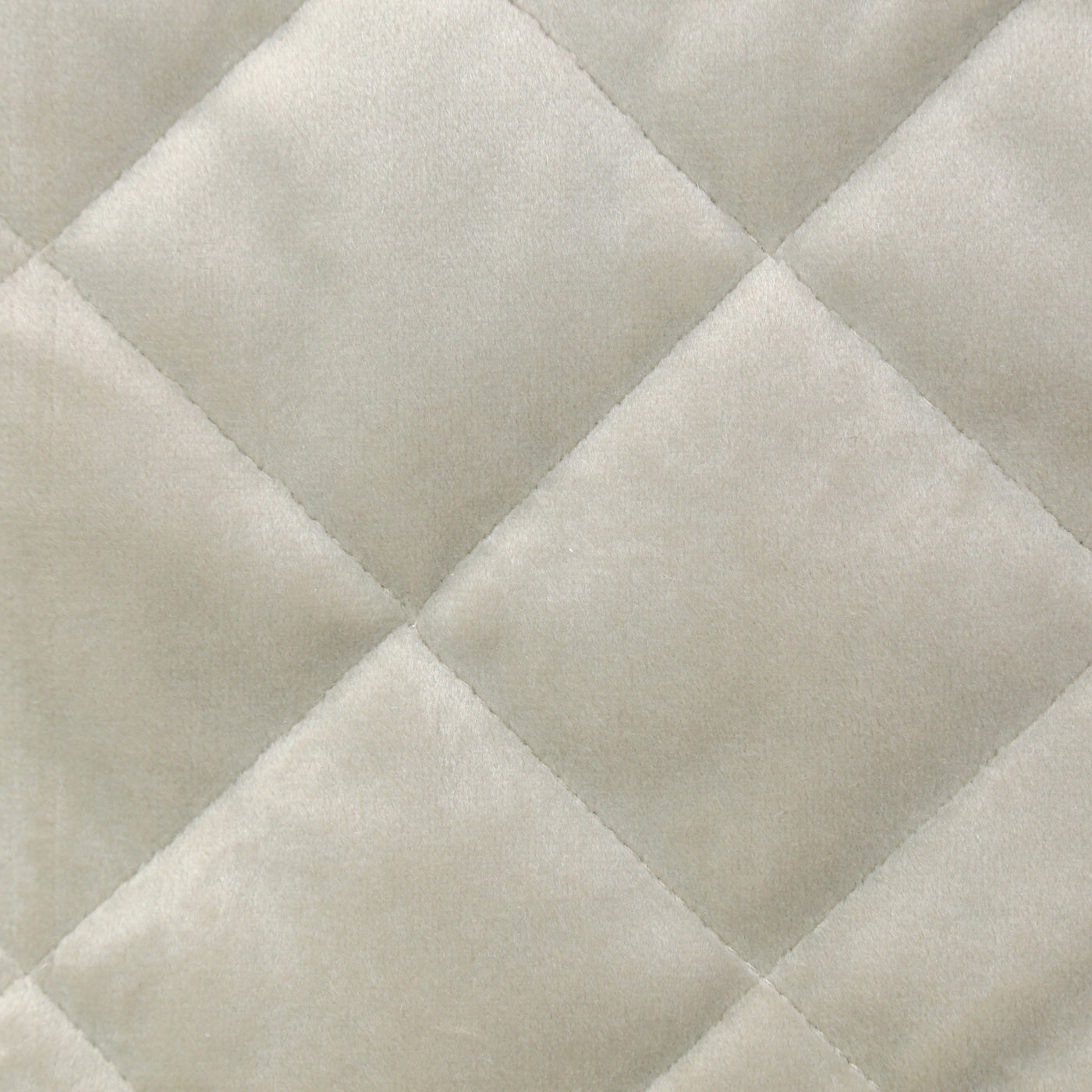 Close-up of ivory velvet quilted in a diagonal diamond pattern.