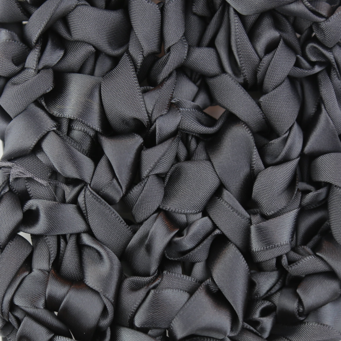 Close-up of charcoal satin ribbon loops forming textured surface of Ann Gish Ribbon Knit pillow.
