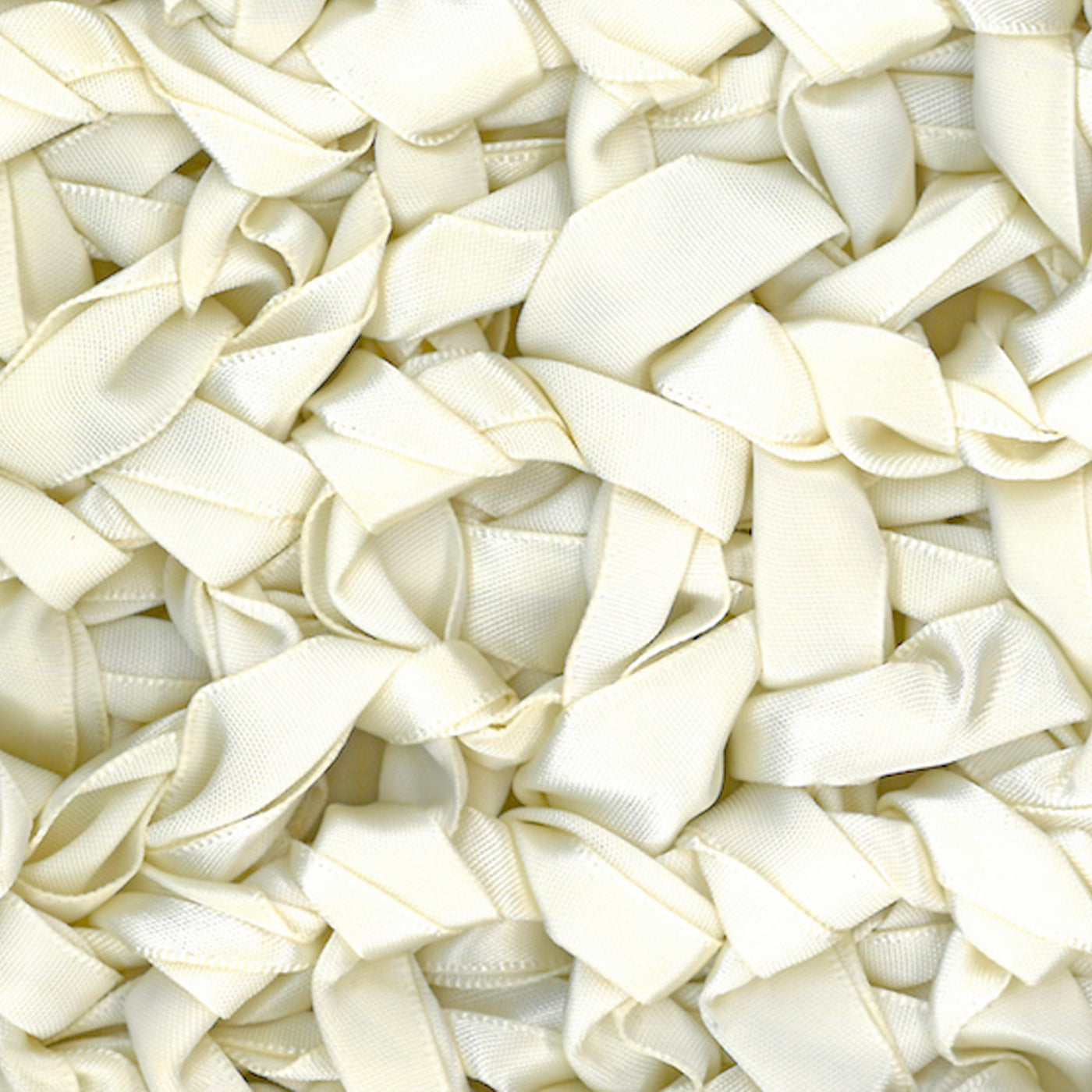 Close-up of ivory satin ribbon loops forming the textured surface of an Ann Gish knit pillow.