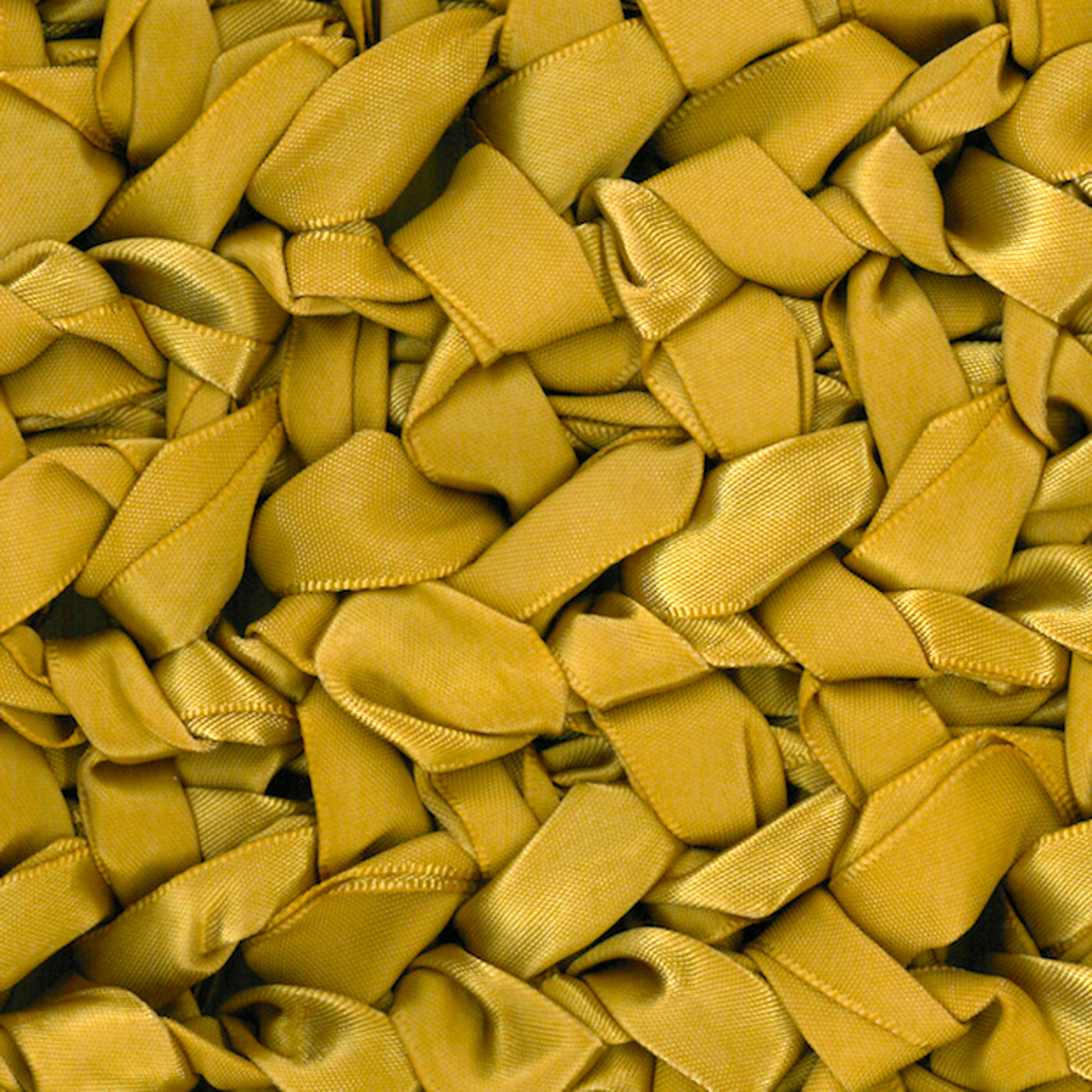 Close-up of Ann Gish Ribbon Knit Pillow in gold satin ribbon loops texture.
