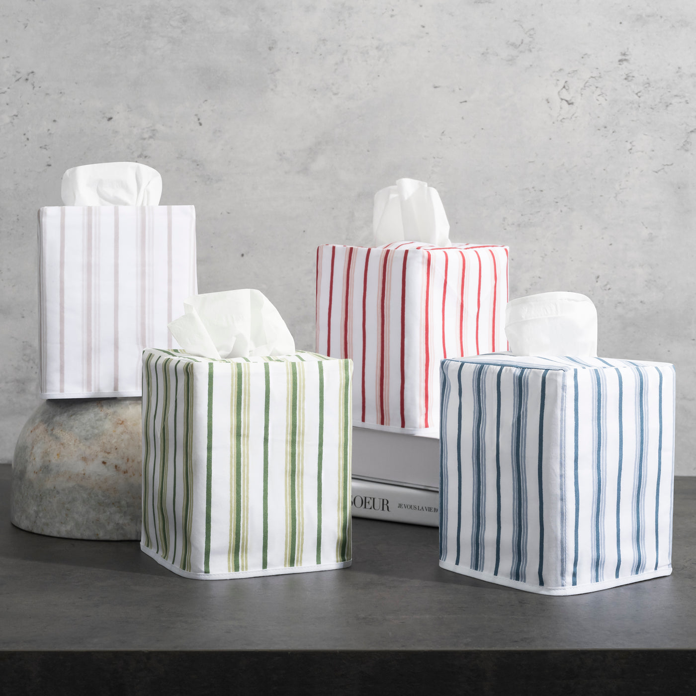 Five Matouk Calypso tissue box covers in striped linen: white, olive, red, blue, and grey.