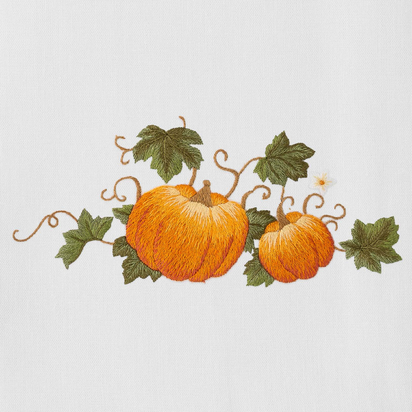 Close-up of orange pumpkin and vine embroidery on ivory linen napkin.