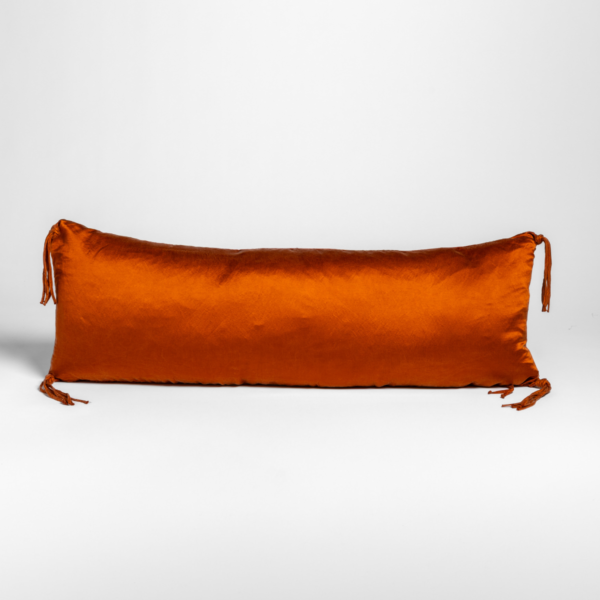 Autumn velvet bolster pillow with tassel ties at each end, front view.