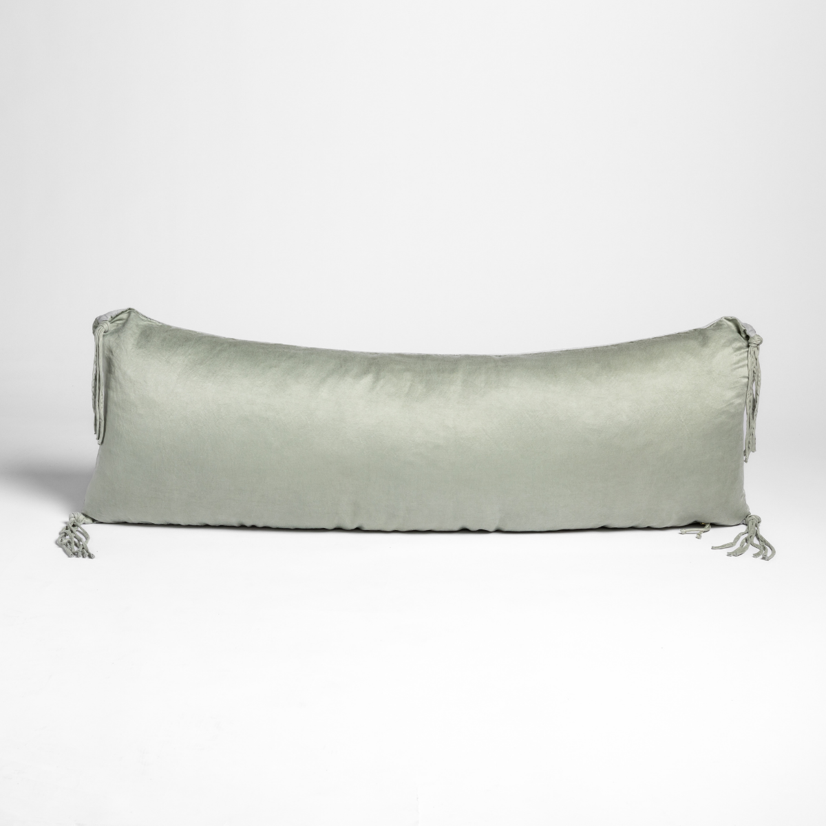 Taline throw pillow in Eucalyptus, long bolster shape with tassel ties at each end.