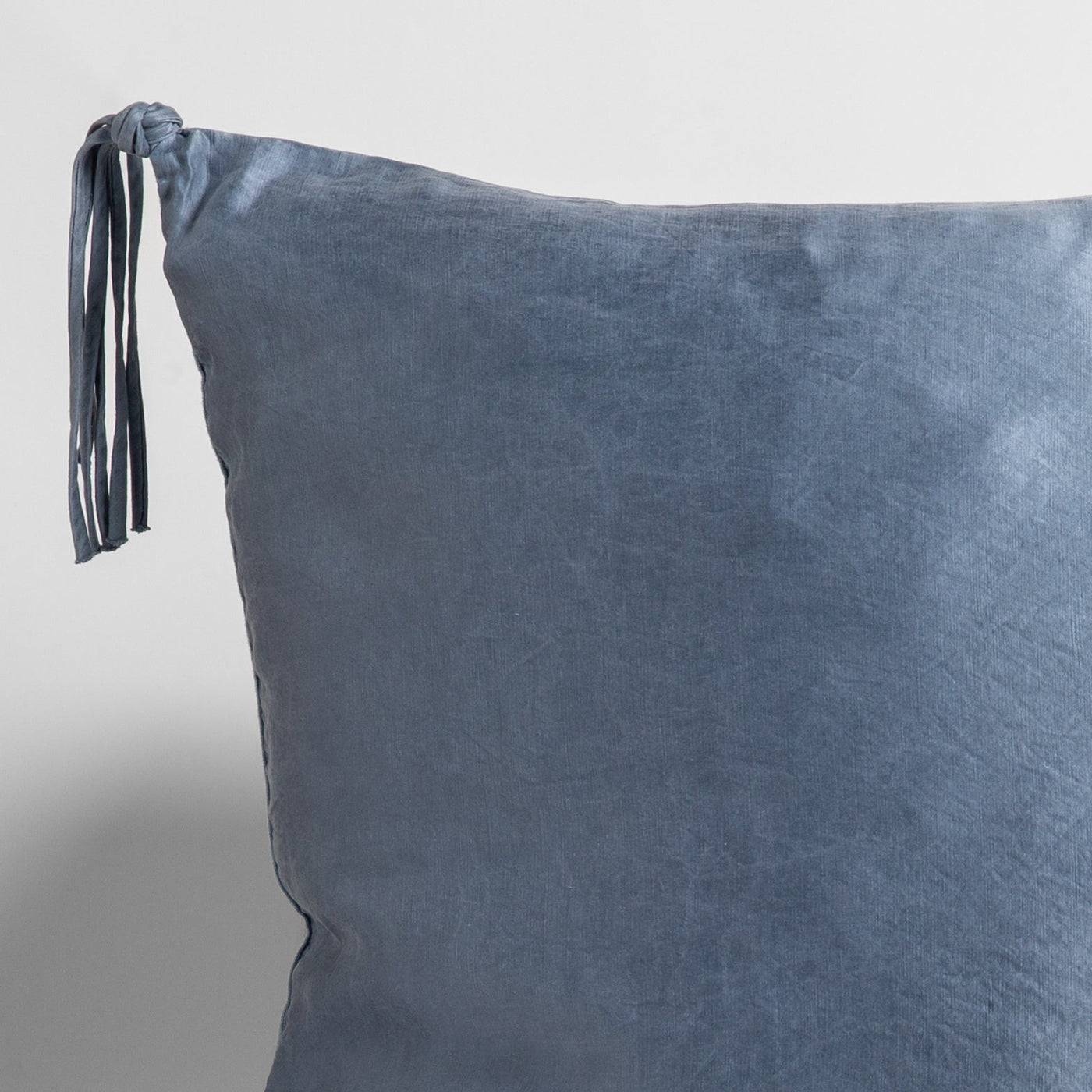 Corner detail of Bella Notte Taline sham in Tahoe Blue, showing leather tassel tie closure.