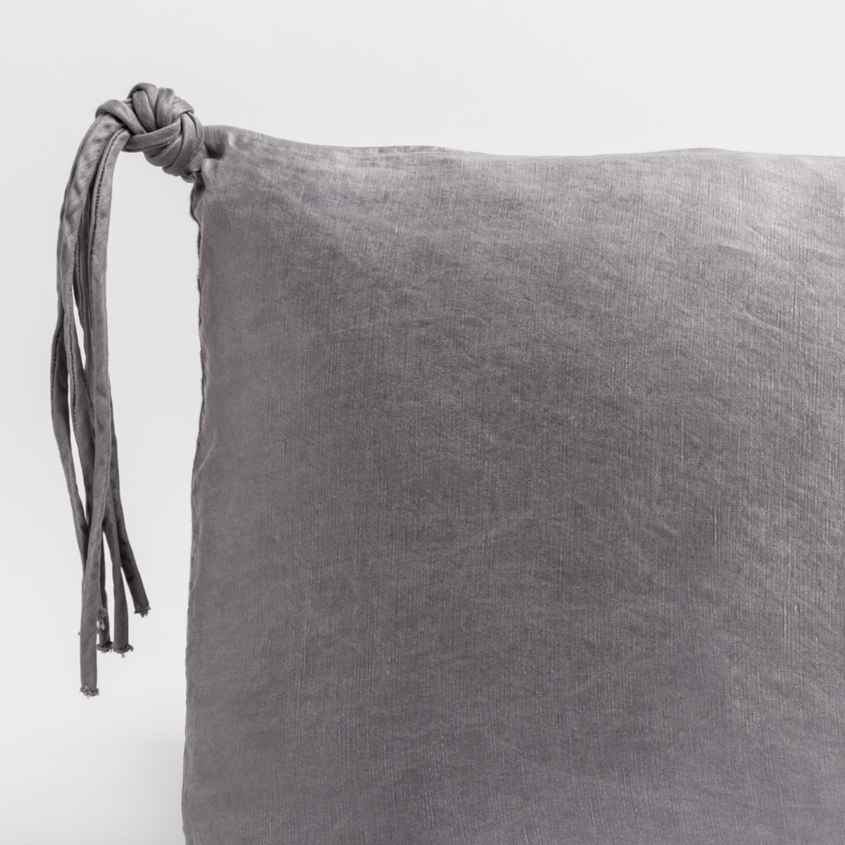 Close-up of French Lavender velvet pillow corner with knotted tassel tie detail.