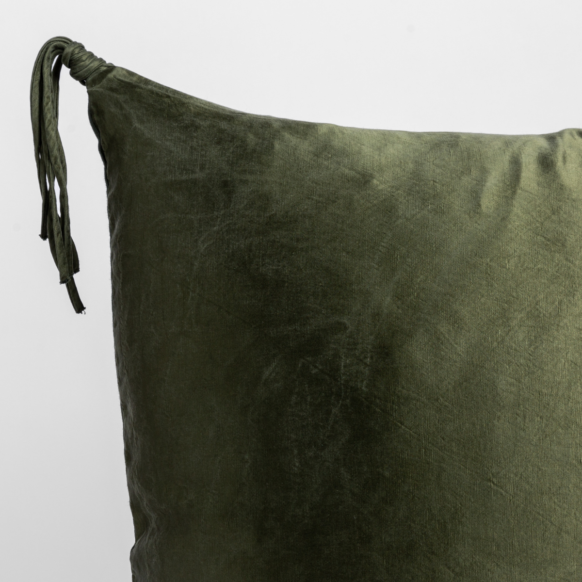 Corner detail of Juniper velvet throw pillow with knotted tassel tie closure.