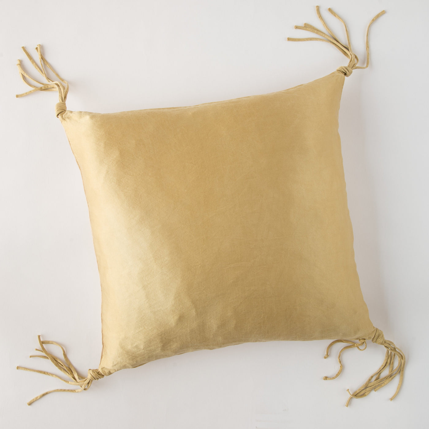 Honeycomb linen throw pillow with knotted tassel ties at all four corners.