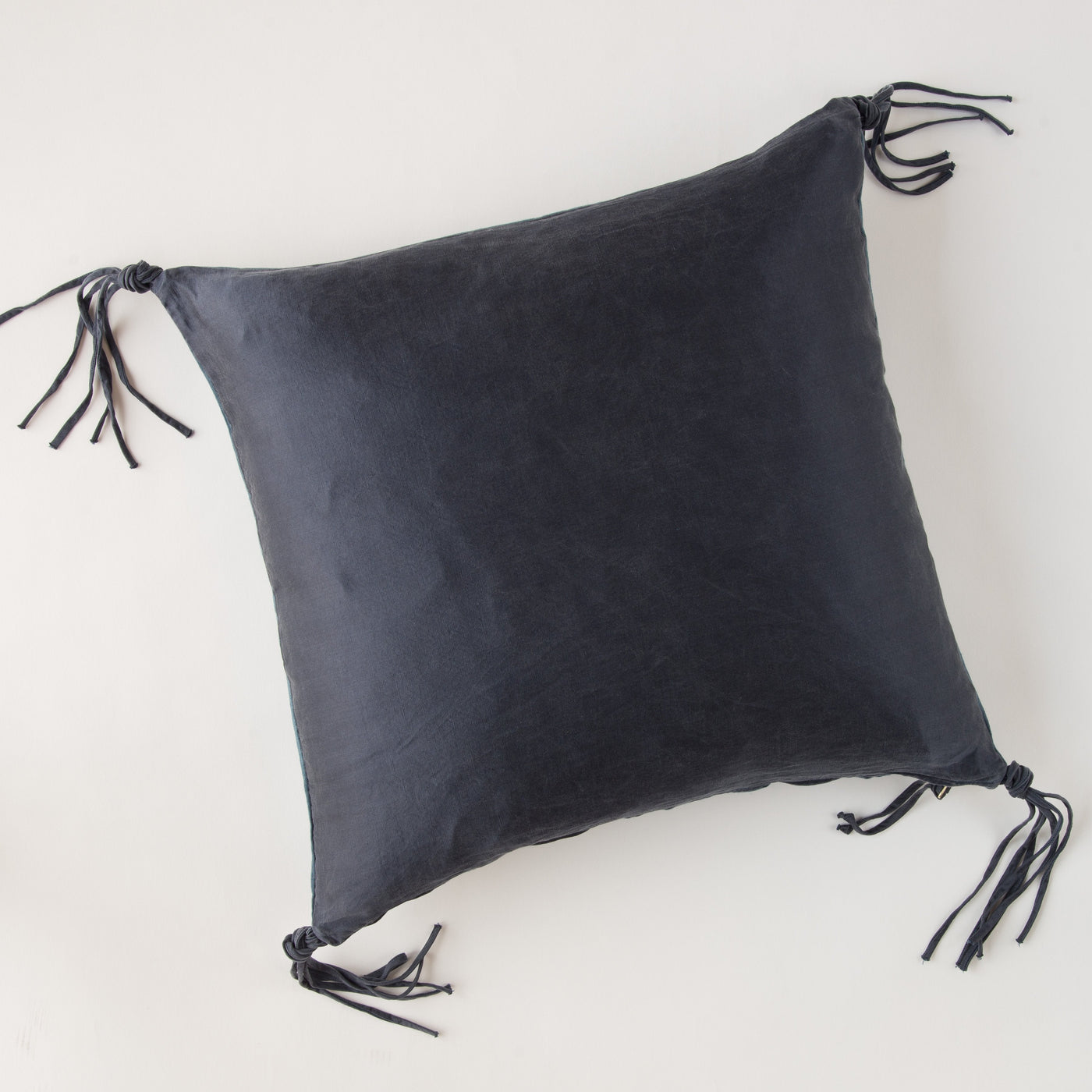 Midnight linen throw pillow with knotted tassel ties at each corner.