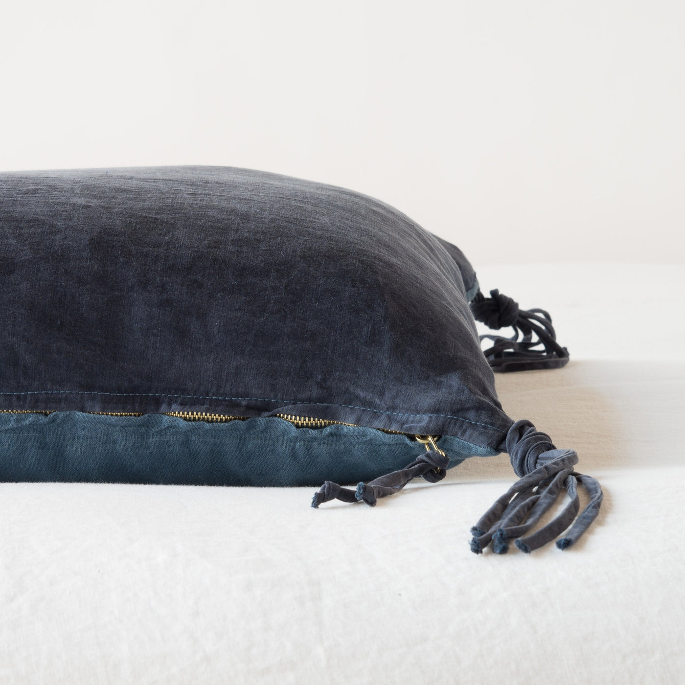 Side view showing brass zipper closure and knotted tassel trim on Midnight velvet throw pillow.