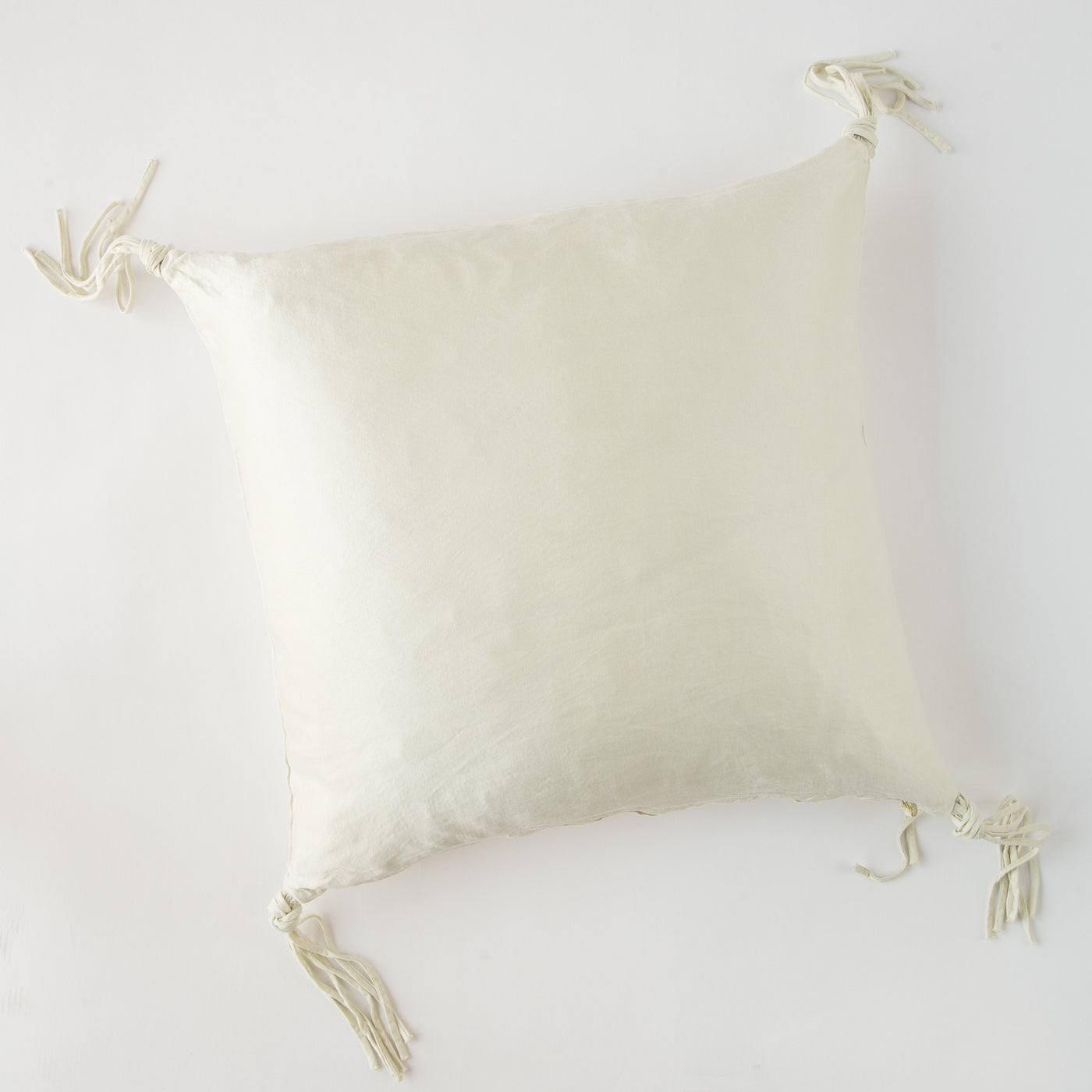 Corner tassel detail on ivory silk-blend Bella Notte Taline throw pillow, flat lay.