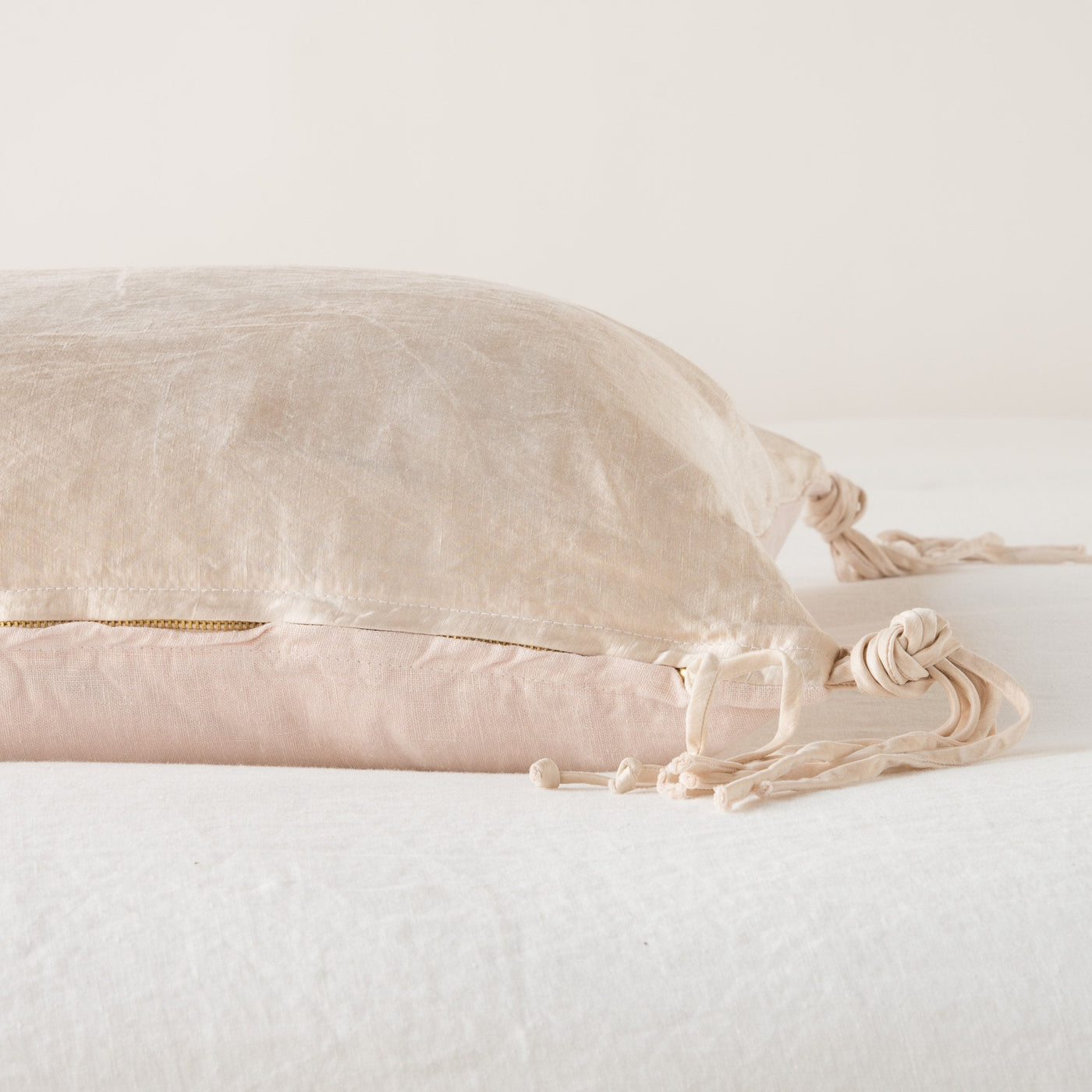 Side view of Pearl Taline throw pillow showing knotted tassel trim and gold zipper detail.