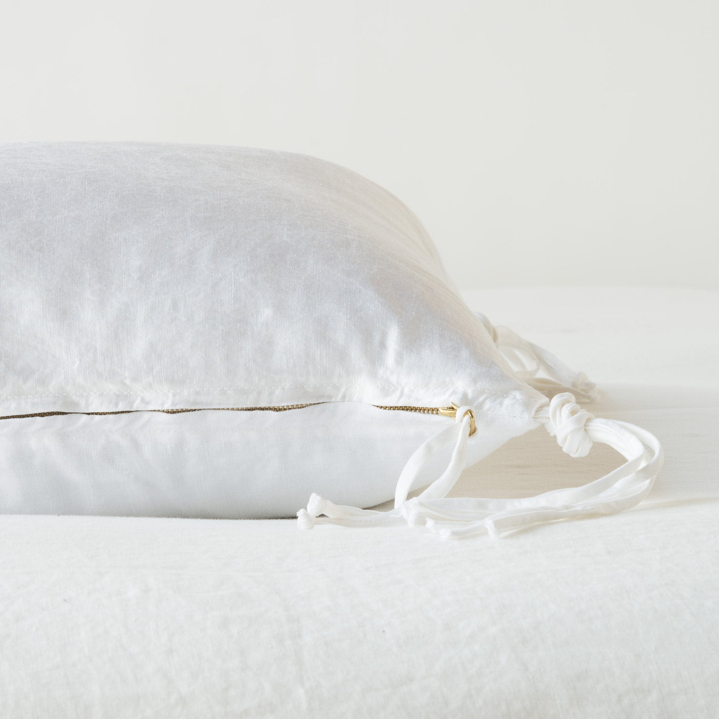 Side view showing gold zipper and white ribbon ties detail on Bella Notte Taline throw pillow.