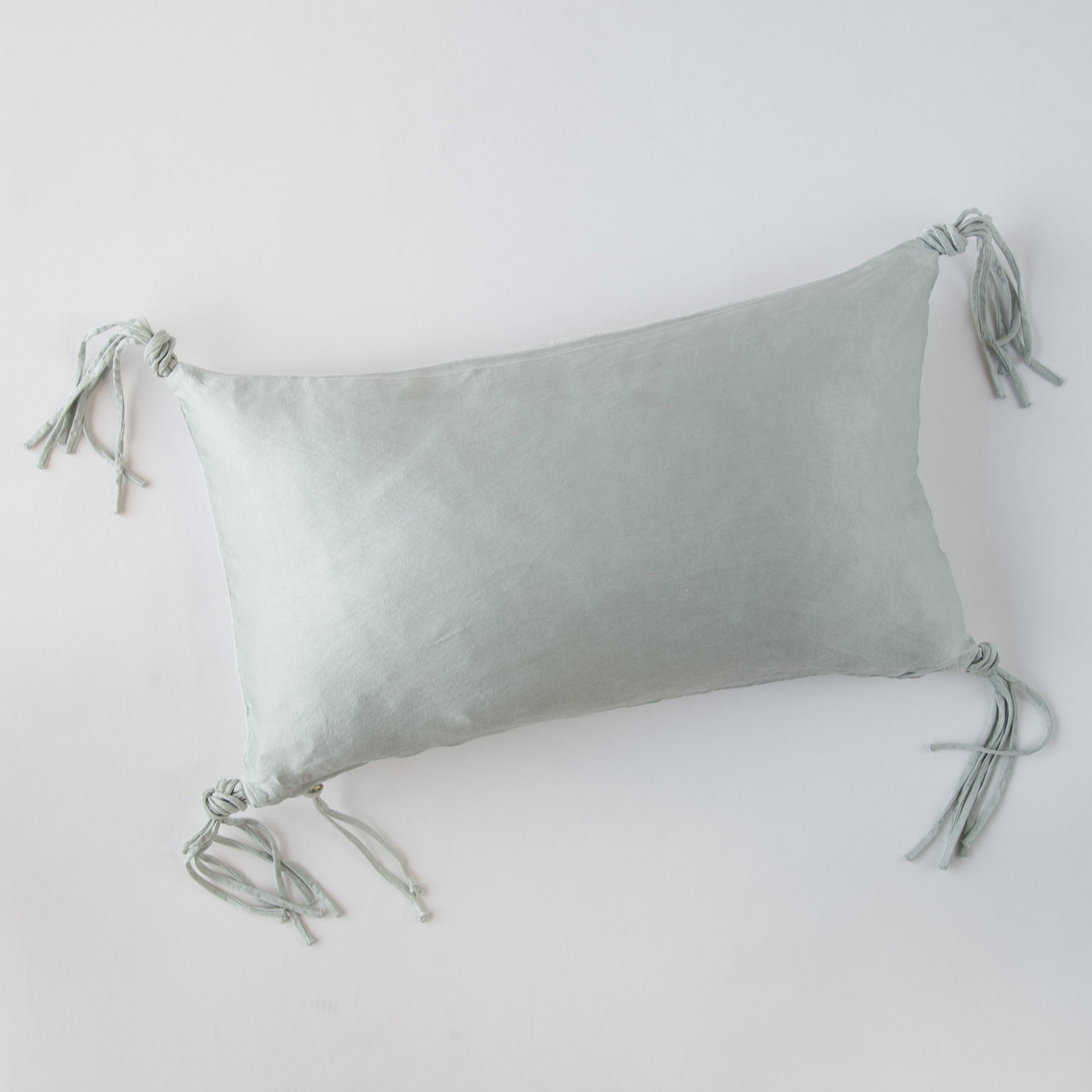Cloud colorway Bella Notte Taline throw pillow showing knotted tassel corners on white background.