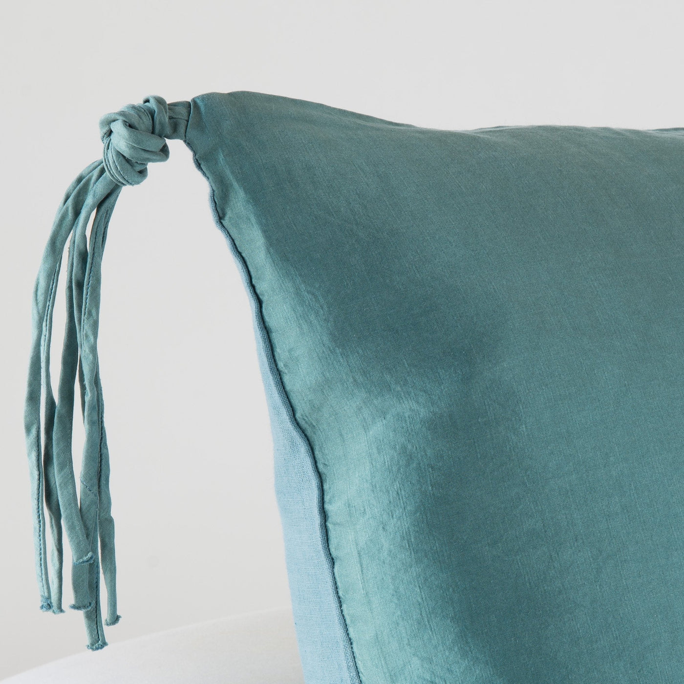 Close-up of Bella Notte Taline sham corner in Cenote, showing knotted tassel detail on washed linen.