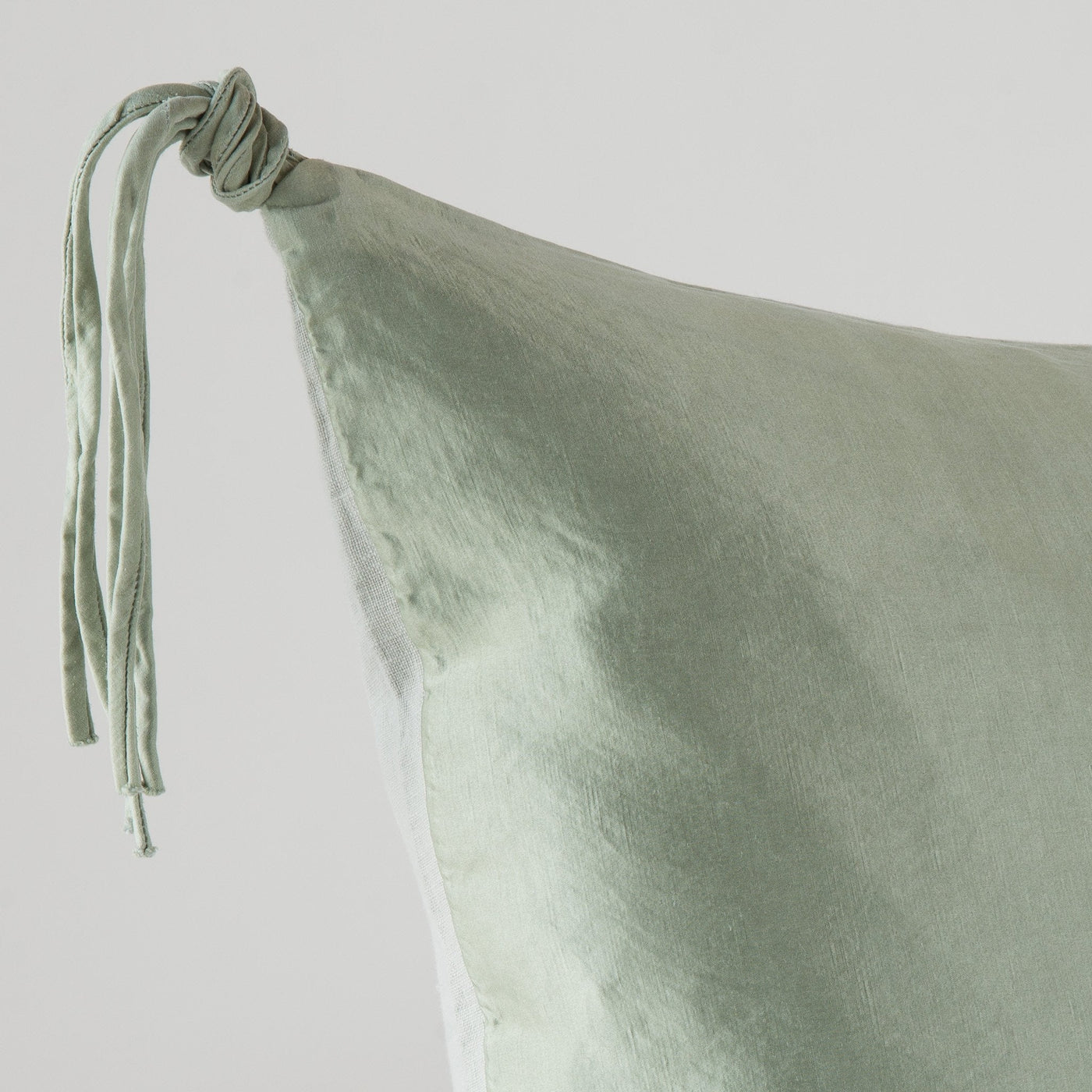 Corner detail of Bella Notte Taline sham in Eucalyptus, showing knotted tassel tie closure.