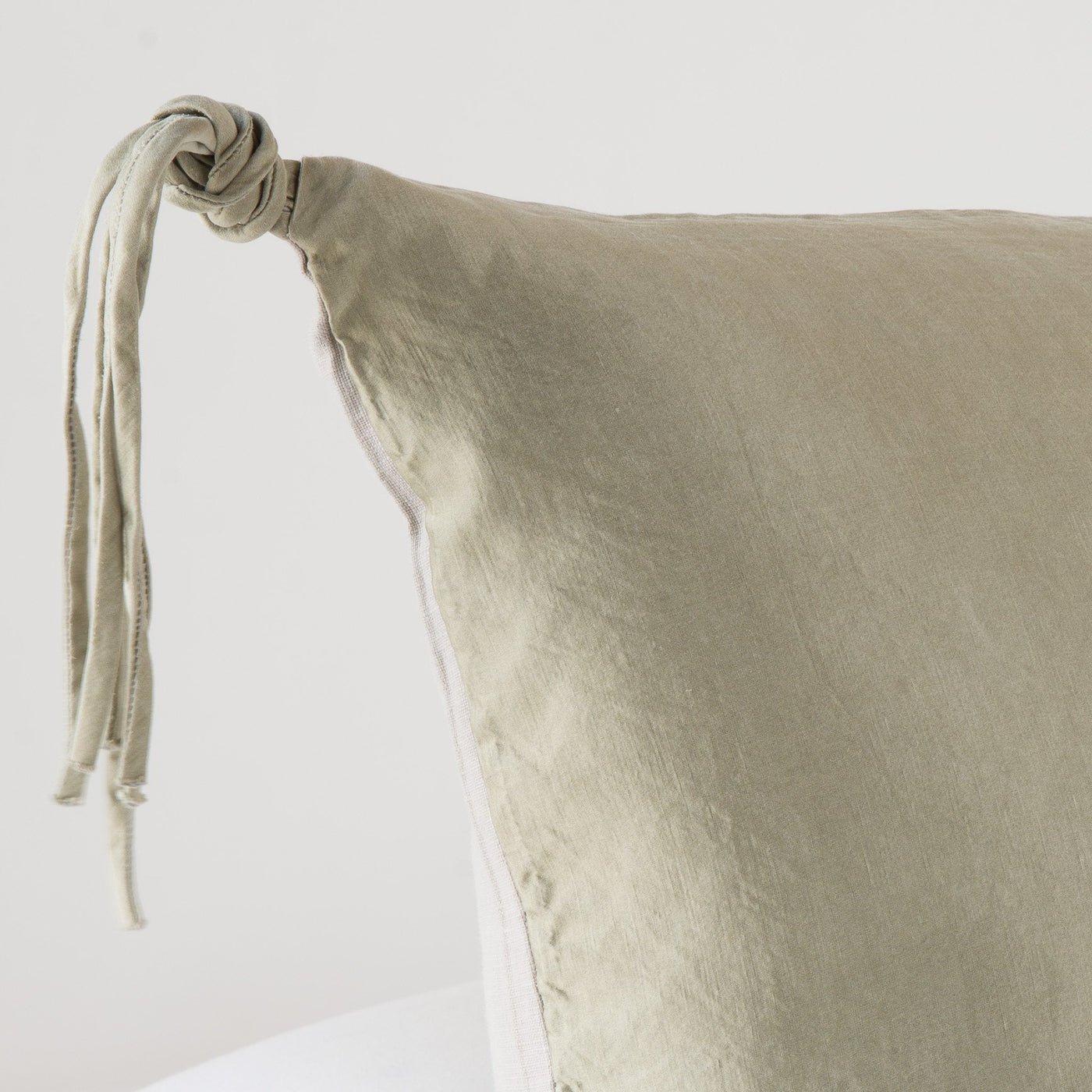 Corner detail of Bella Notte Taline sham in Fog, showing knotted tassel trim on washed linen.