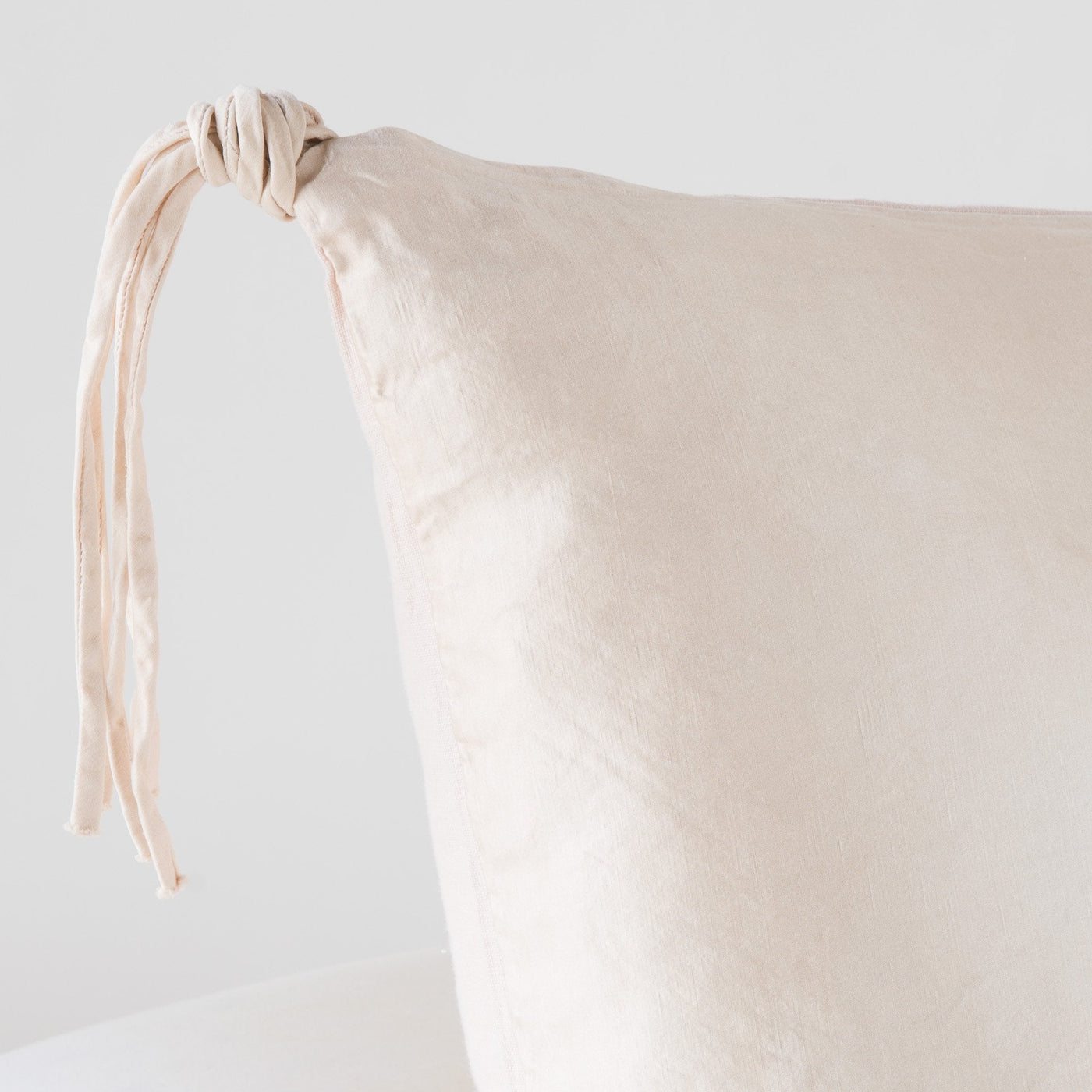 Close-up of Pearl linen sham corner with knotted fabric tie detail.