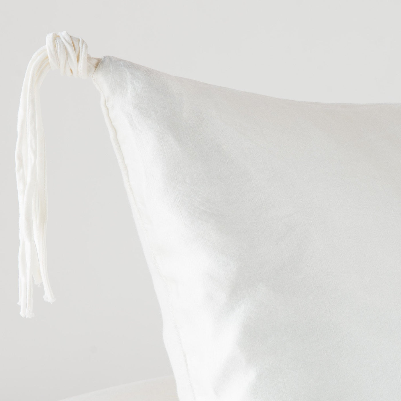 Corner detail of Bella Notte Taline sham in Winter White, showing knotted tassel tie.
